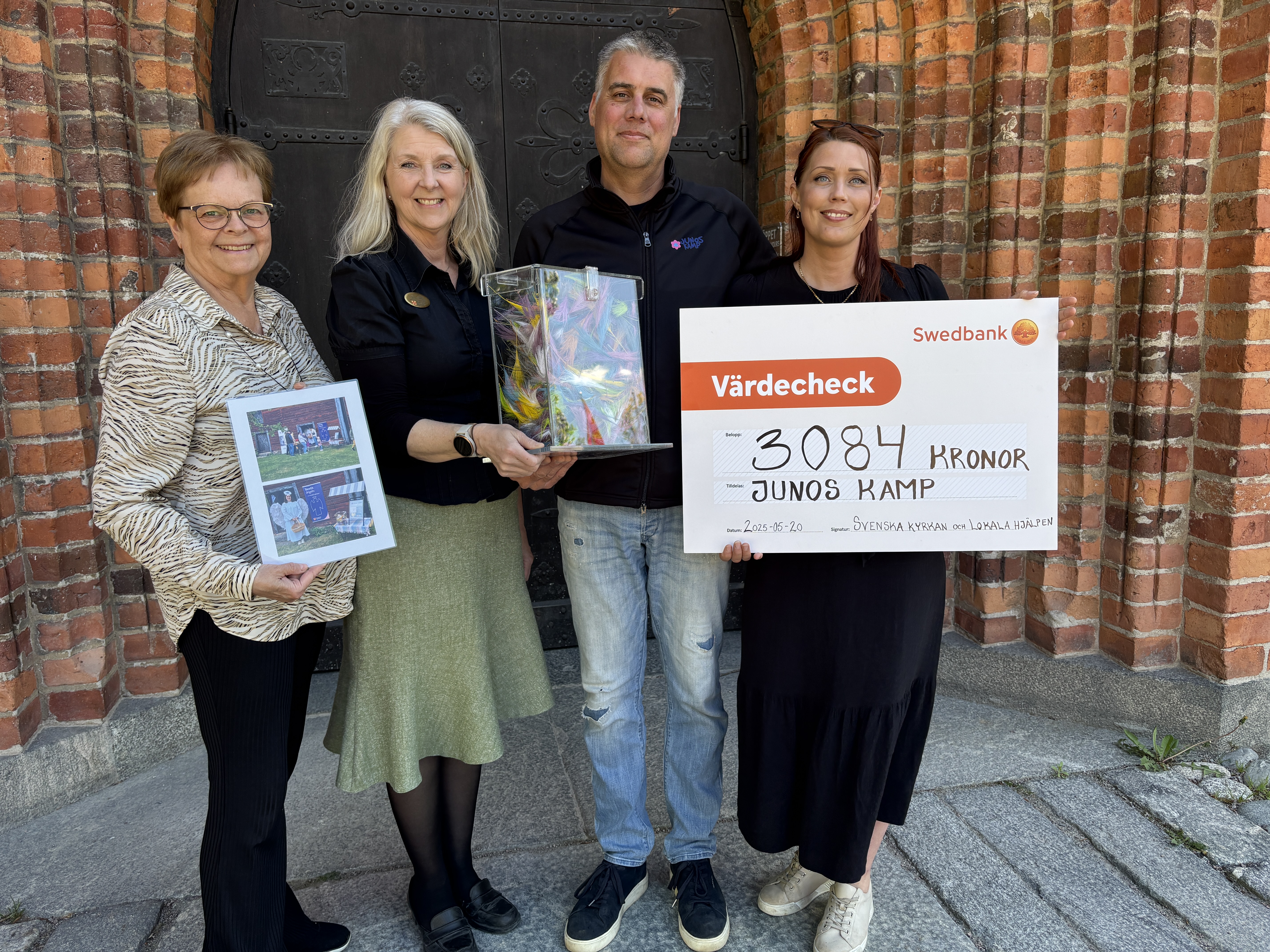 Beartice Hage, Ingela Tillbom, Gunnar Zeek och Amanda Gahm. utanför Domkyrkan i Västerås med värdecheck som ska överlämnas tilll Junos kamp.