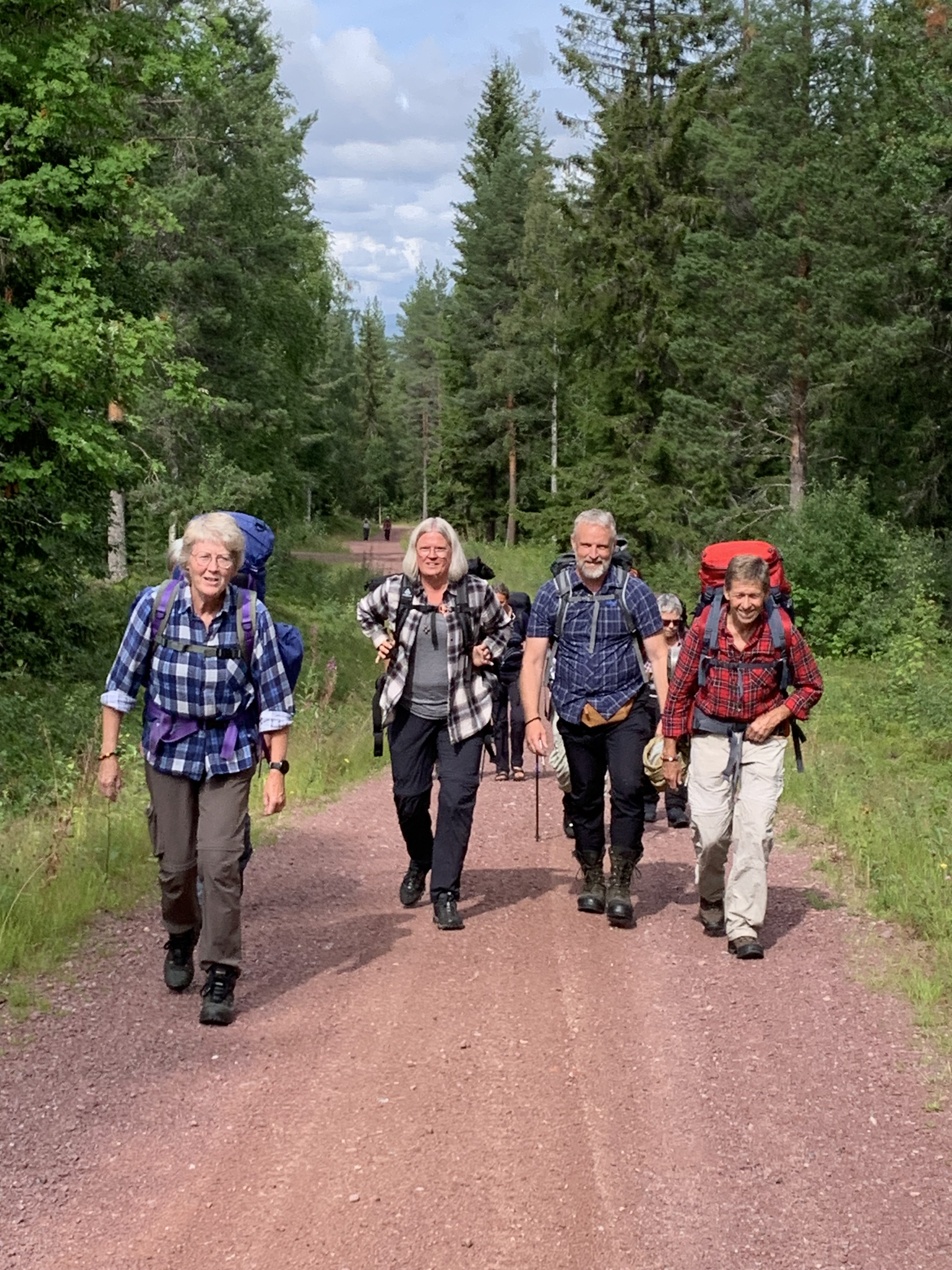Foto taget framifrån på en grupp personer som kommer gåendes på en grusväg under pilgrimsvandring