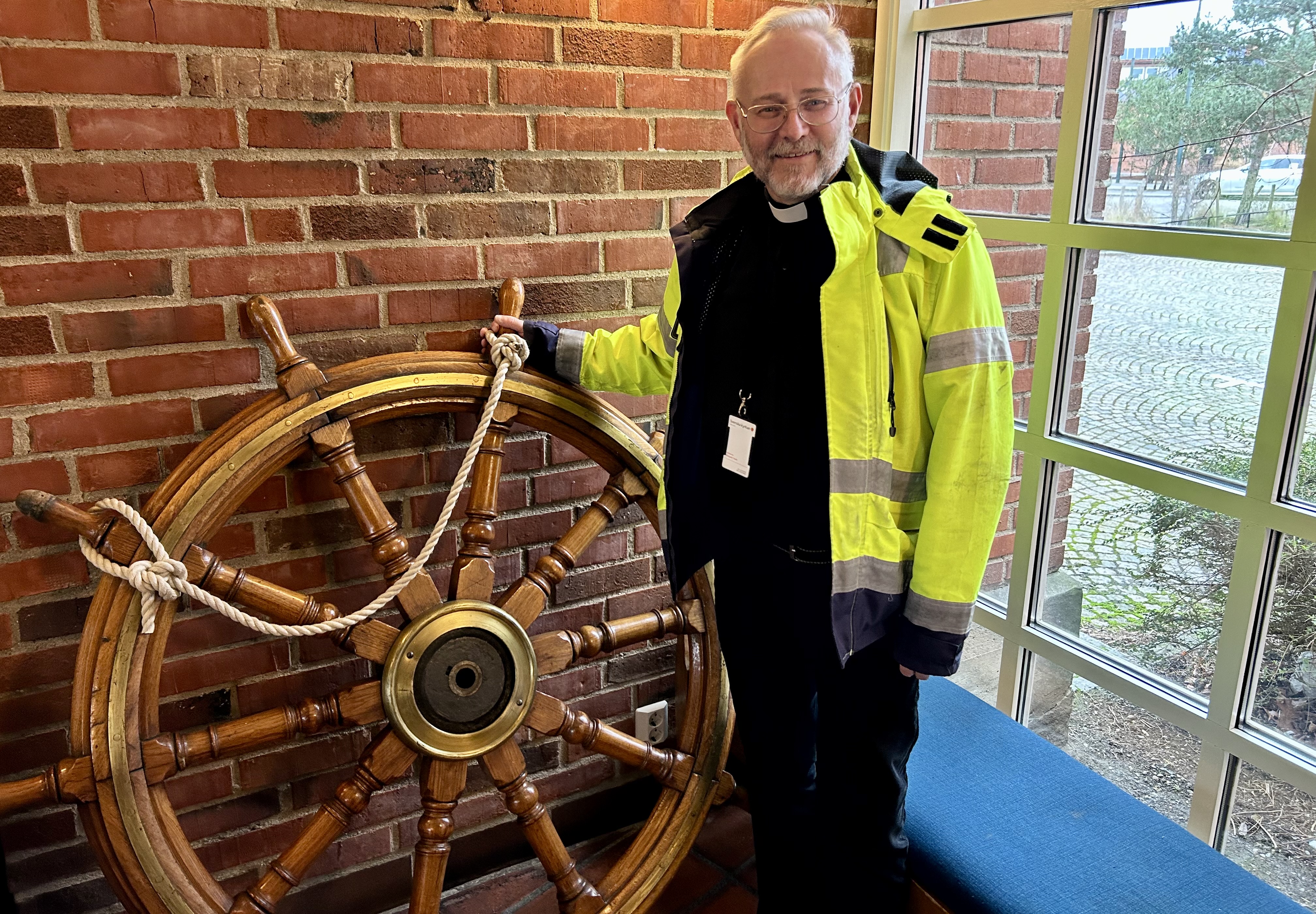 En man i gul reflexjacka håller i ett roder.