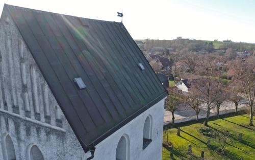 Vitkalkad kyrka med svart tak.