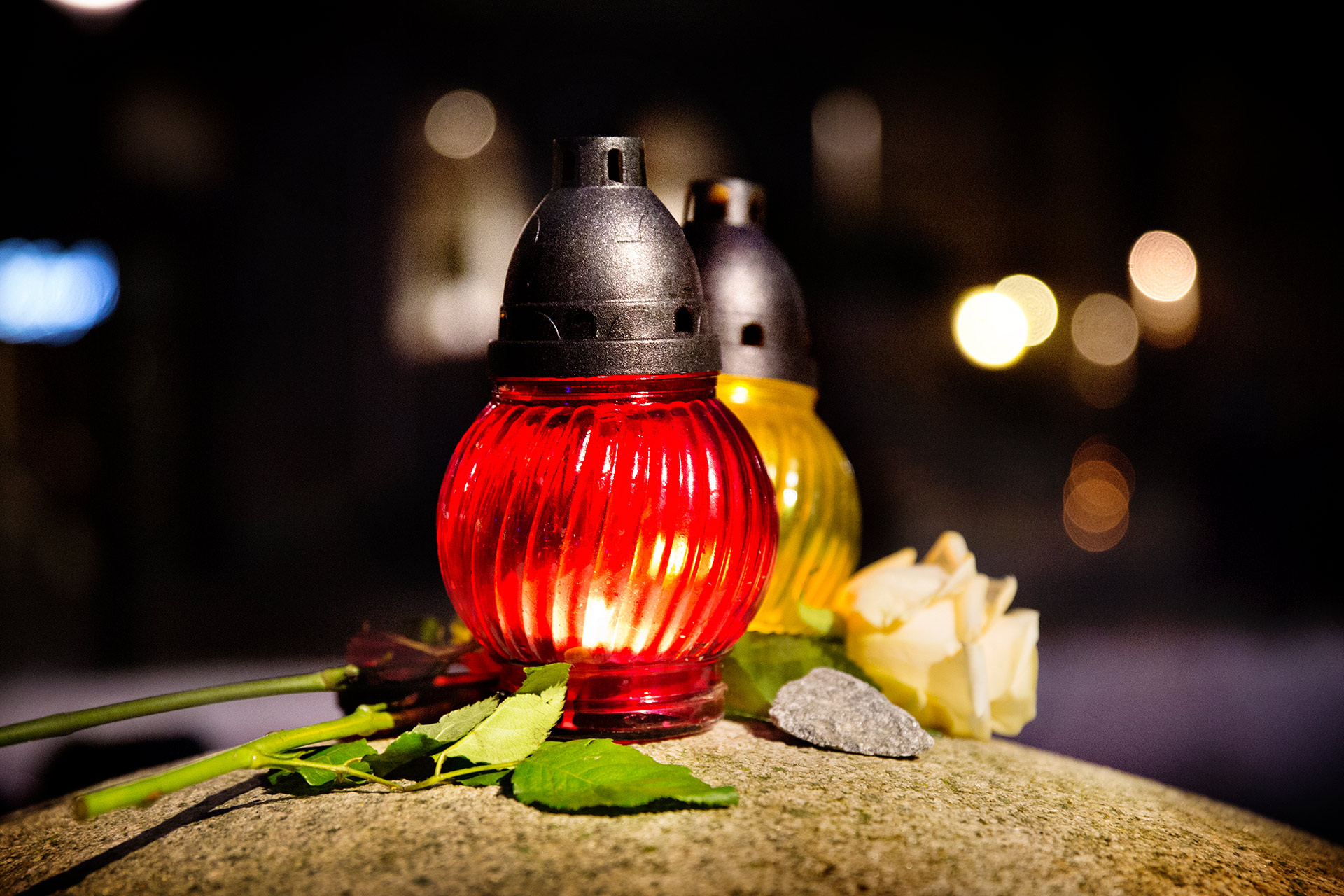 Ljuslyktor och rosor lyser upp i mörkret.