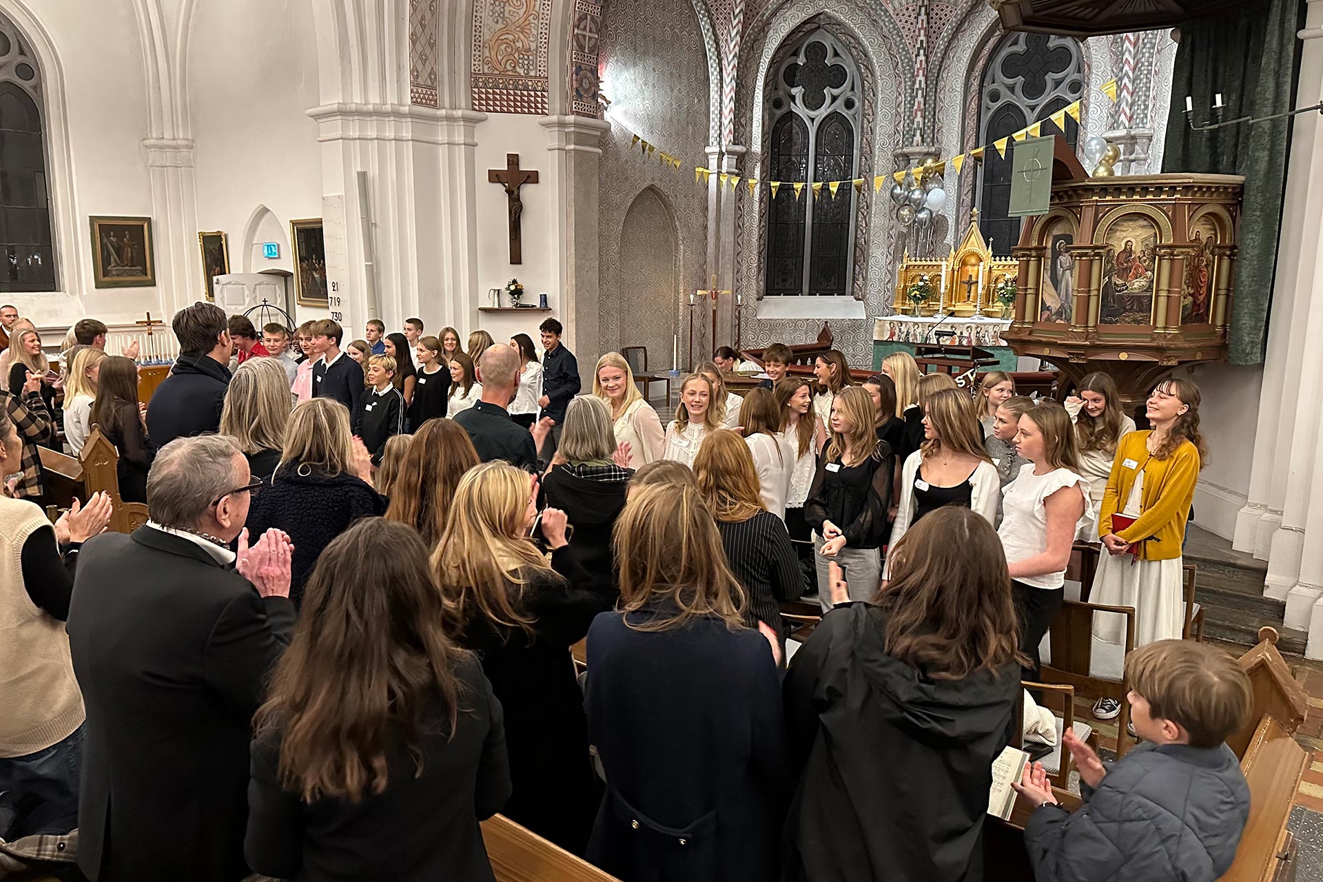 Ungdomar står framme i koret i kyrkan.
