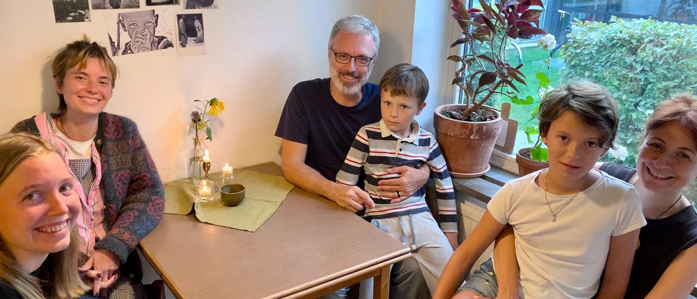 Fyra vuxna och två barn sitter runt ett köksbord.