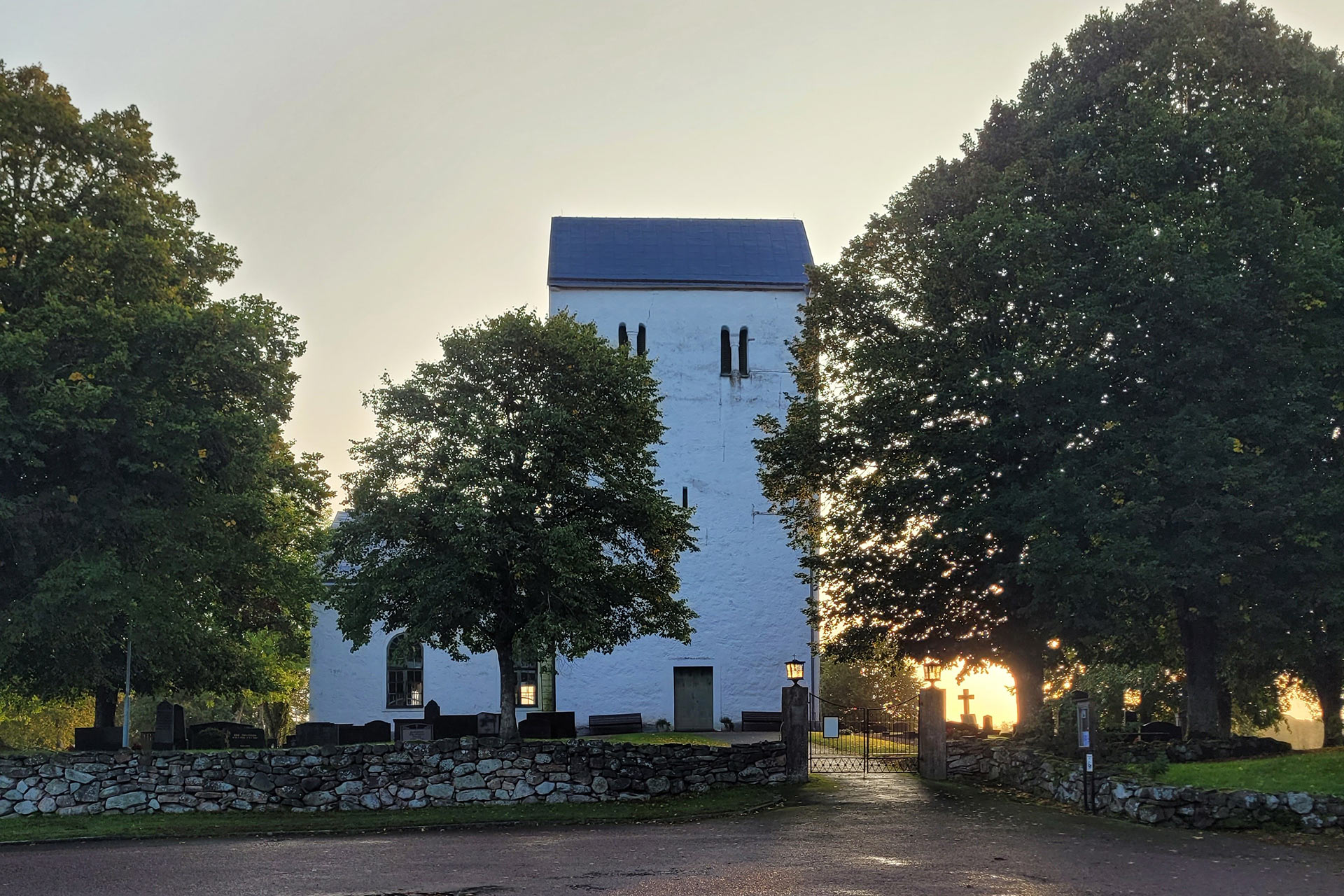 Vitkalkad kyrka i skymningsljus.