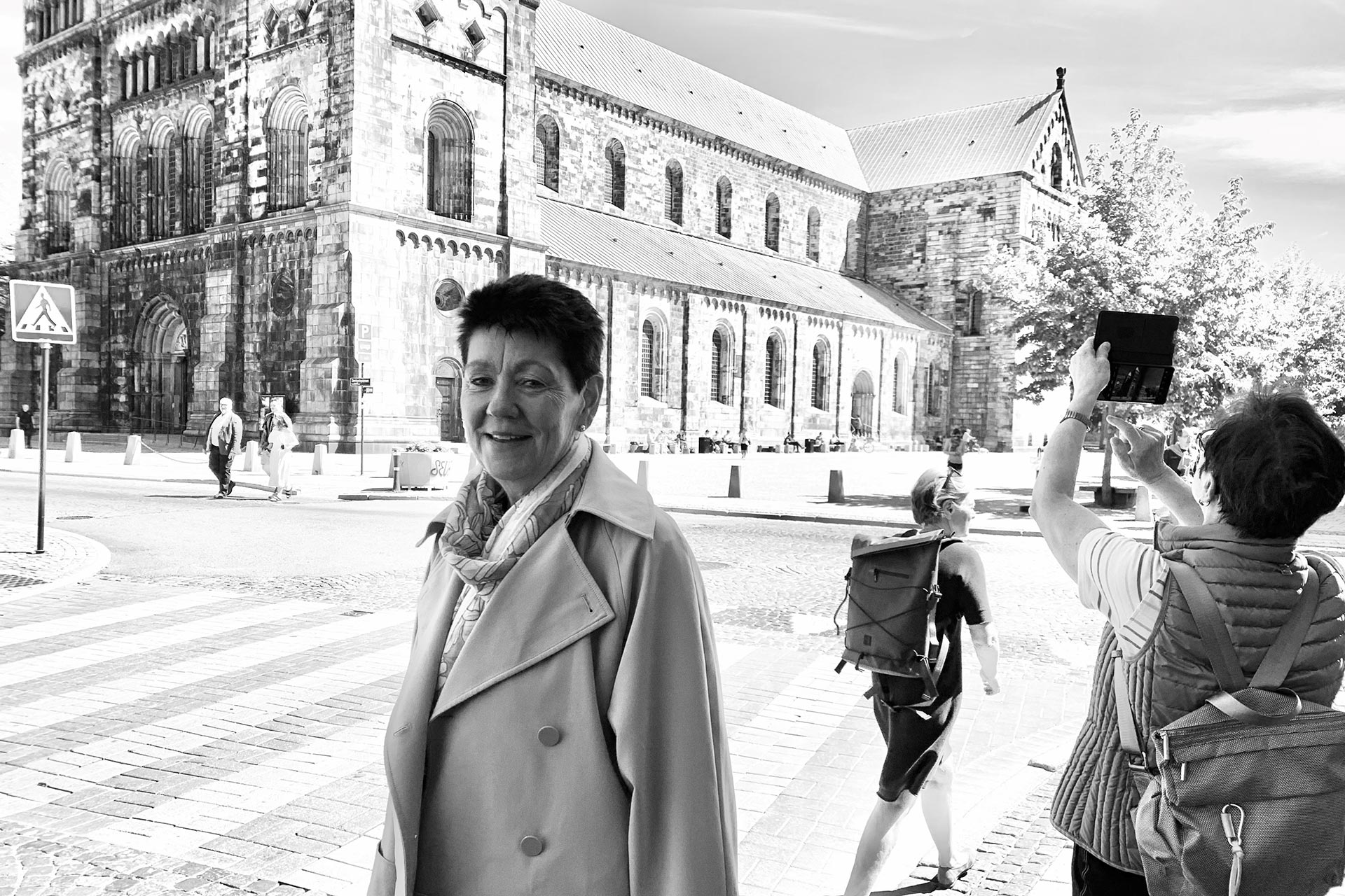 Medelålders kvinna med kortklippt mörkt hår passerar franmför Lunds domkyrka.