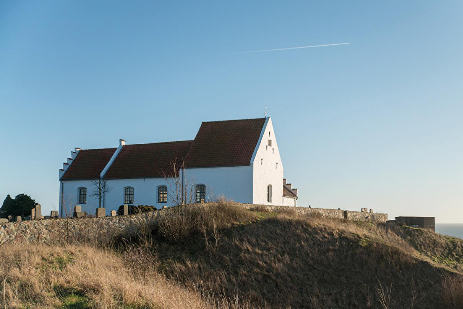 Vitkalkad kyrka med utsikt över havet.