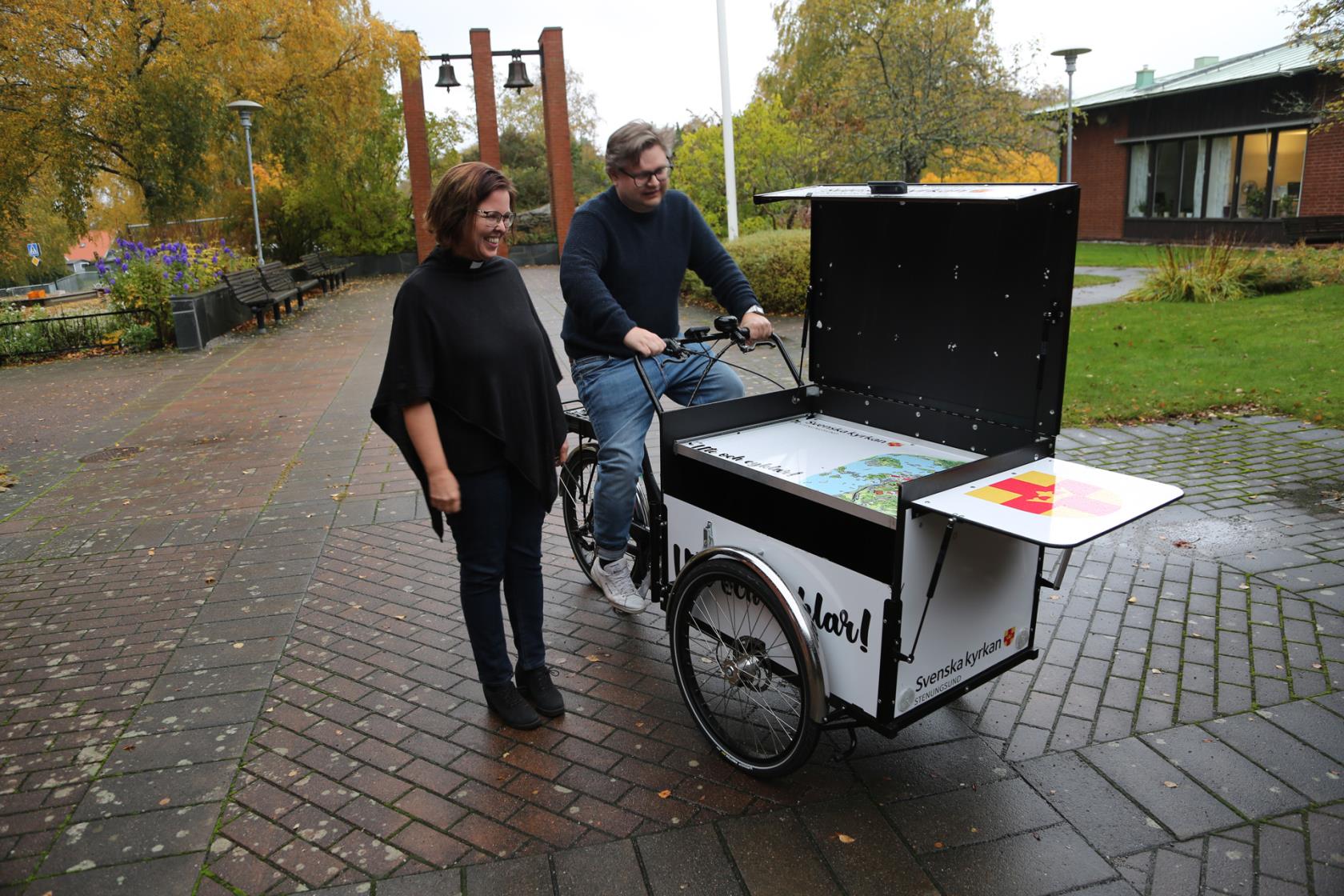 Kyrkoherde Elinor Johansson och kommunikatör Per Jonsson med församlingens lådcykel.