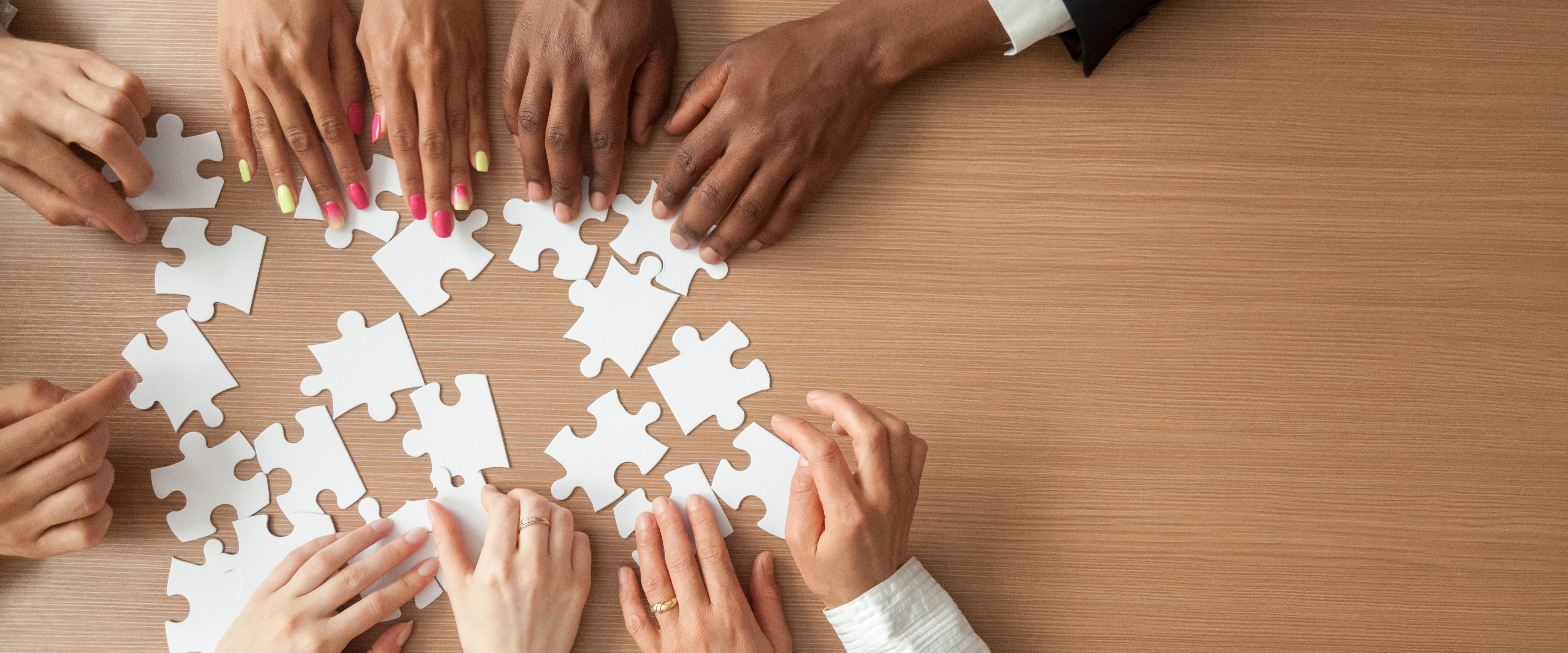 Händer som lägger pusselbitar på ett bord.