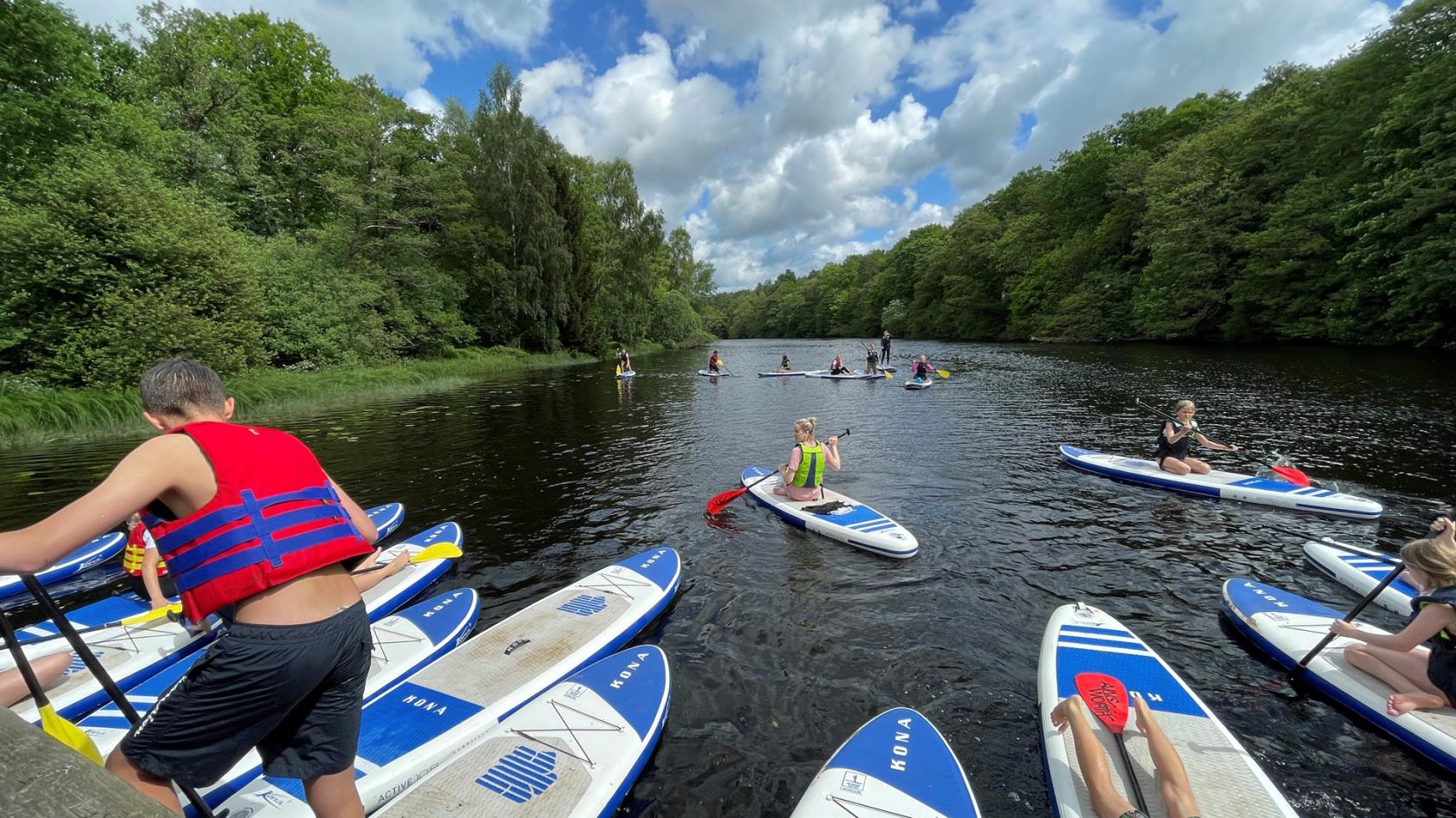 Barn och ungdomar i Harplinge-Steninge församling testar på sommaraktiviteten SUP, Stand Up Paddle, i Nissan. 