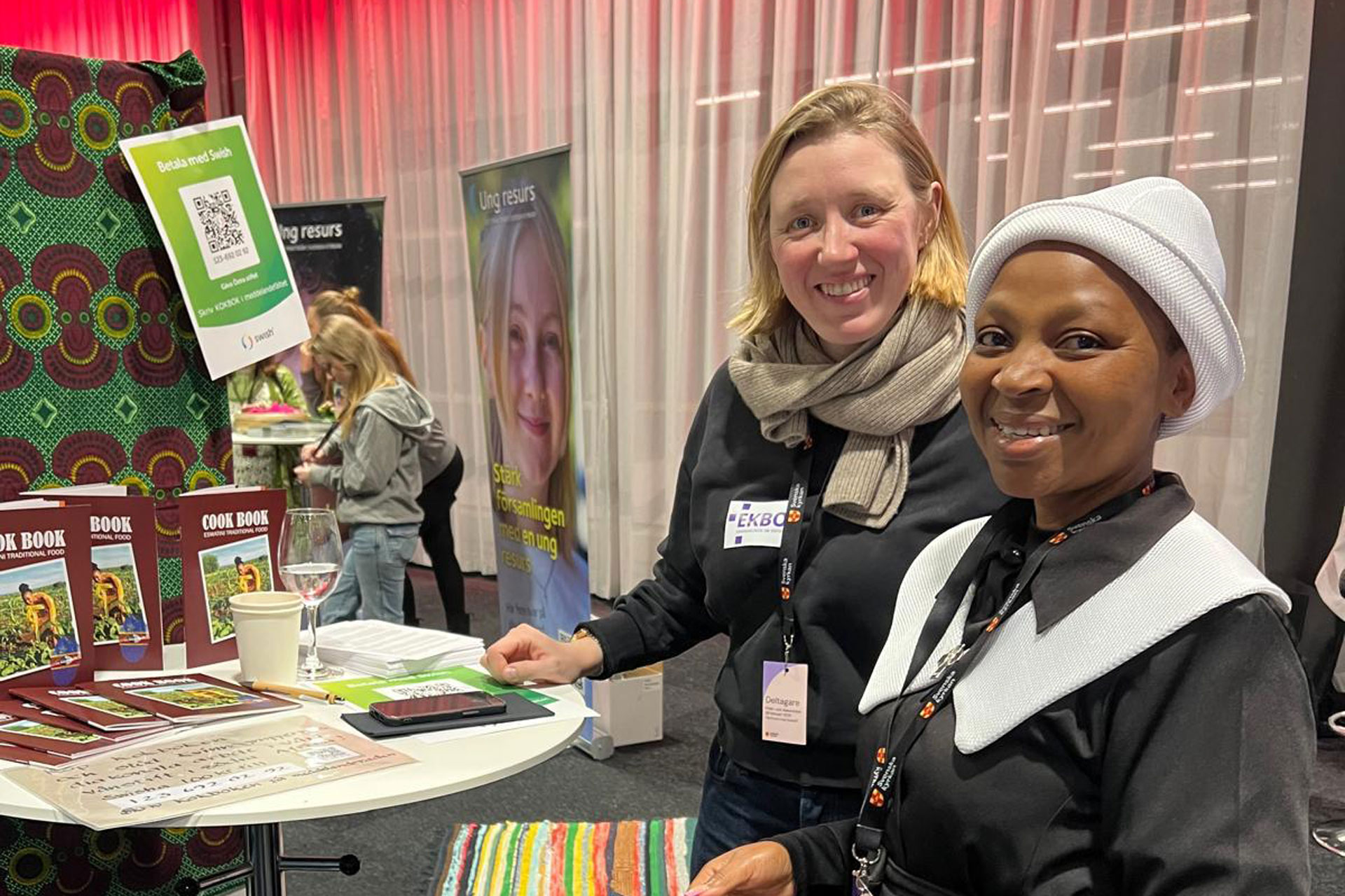 Två kvinnor från Göteborgs olika vänstift står vid en monter och ler mot kameran.