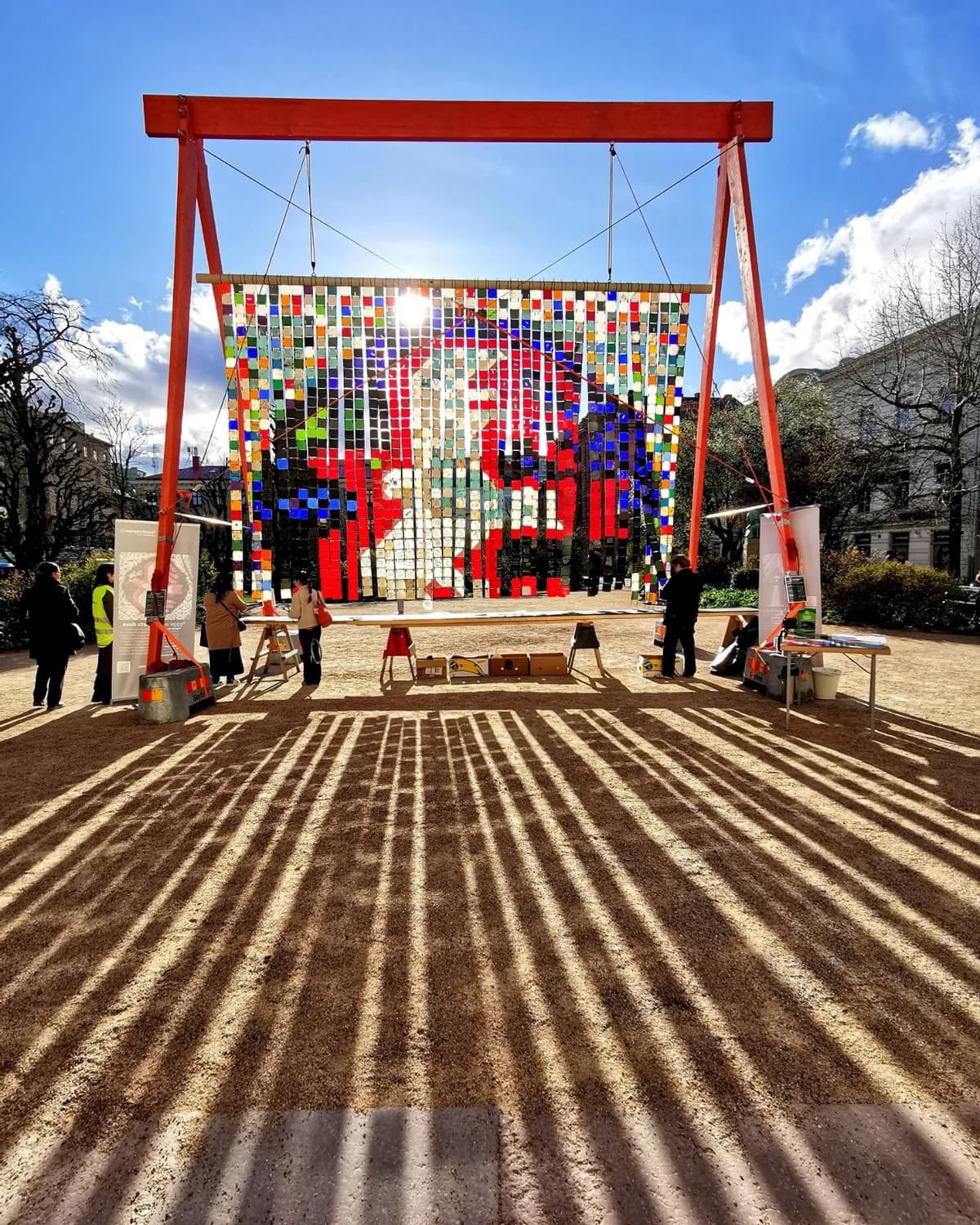 Solens strålar skapar ett randmönster på marken där det lyser genom mosaikkonstverket Hoppets duva på domkyrkoplan i Göteborg.