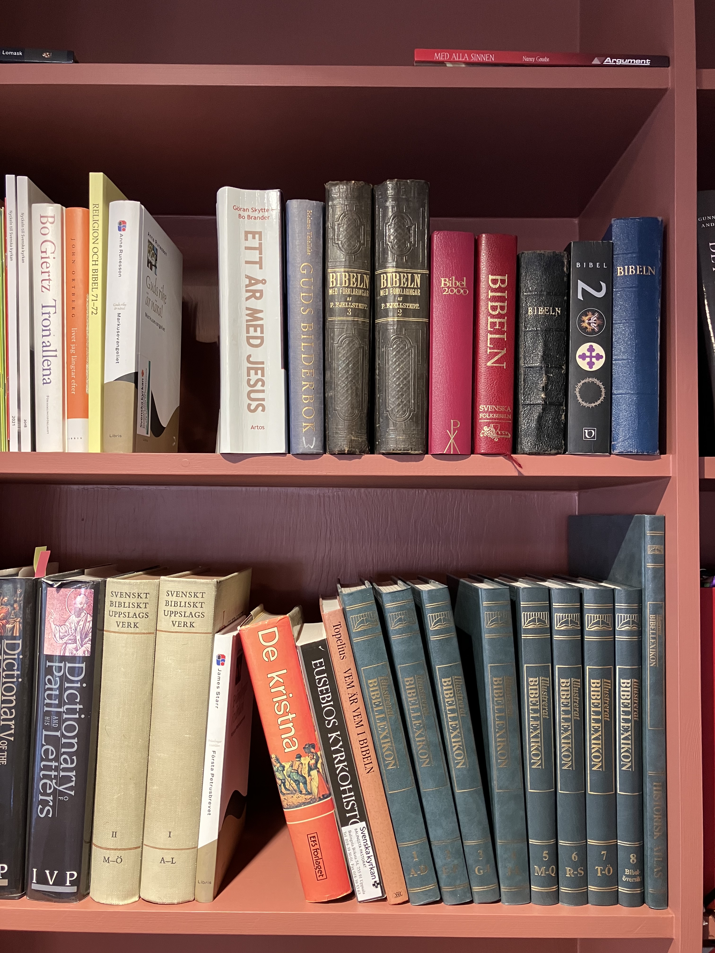 Bild på en bokhylla med böcker i Balingsta pastorsexpedition. Böckerna som syns är biblar och bildkommentarer. 