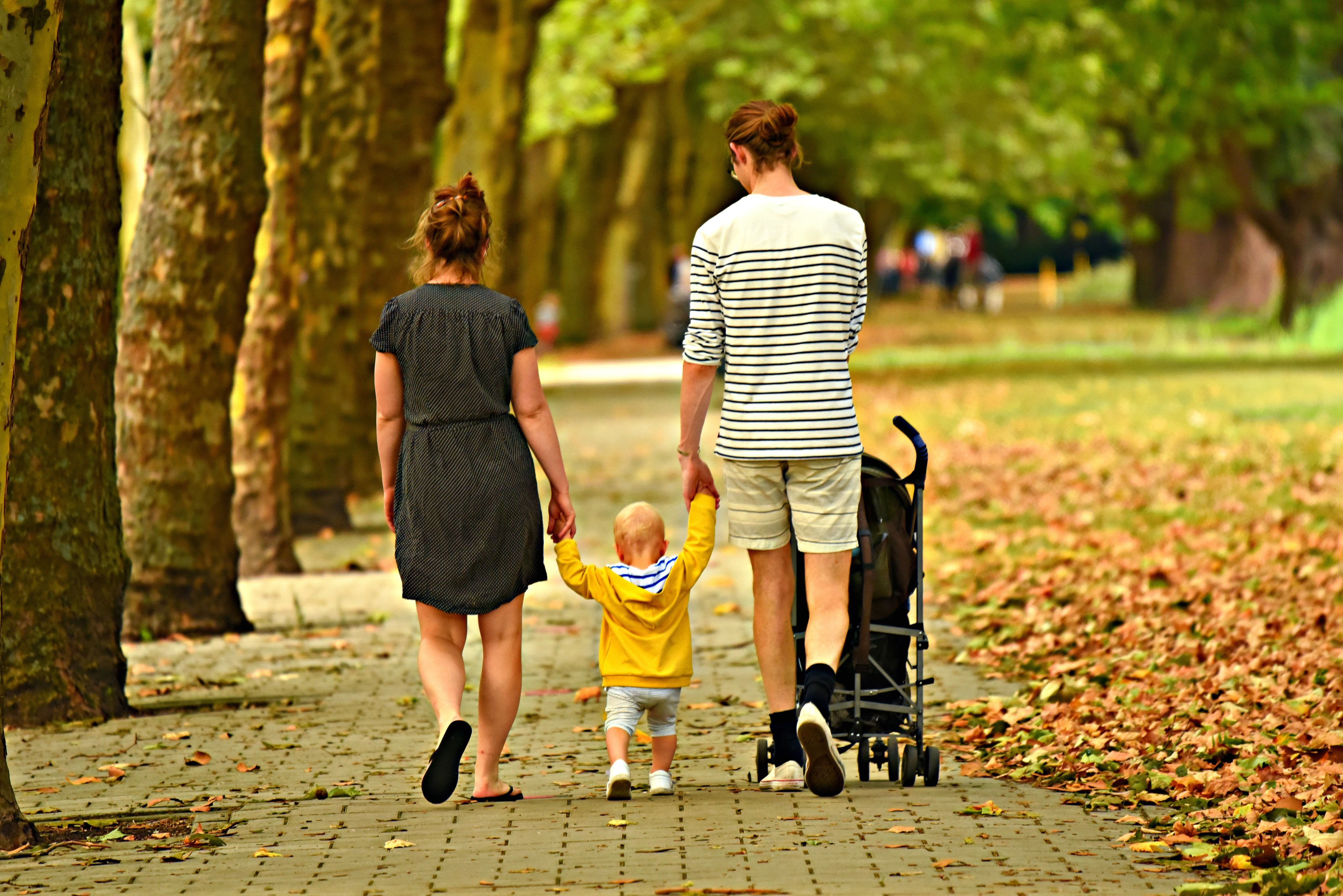 En kvinna och en man med ett litet barn på promenad