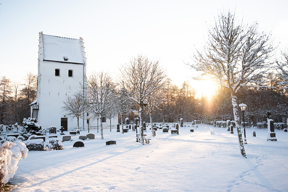 En medeltidskyrka täckt av snö. Solen skiner.
