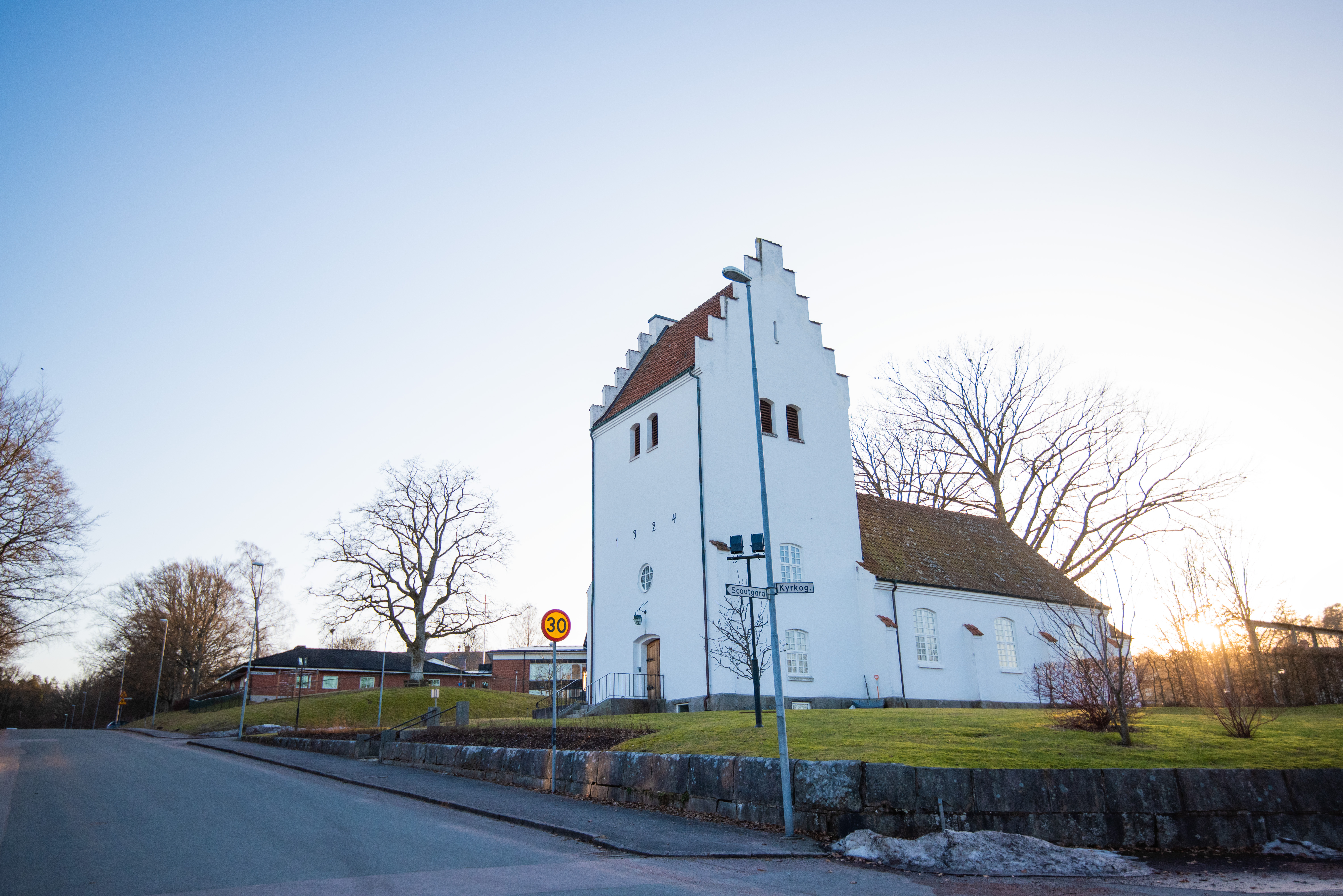 En vit kyrka i en by. Kvällssolen lyser och det är vår.