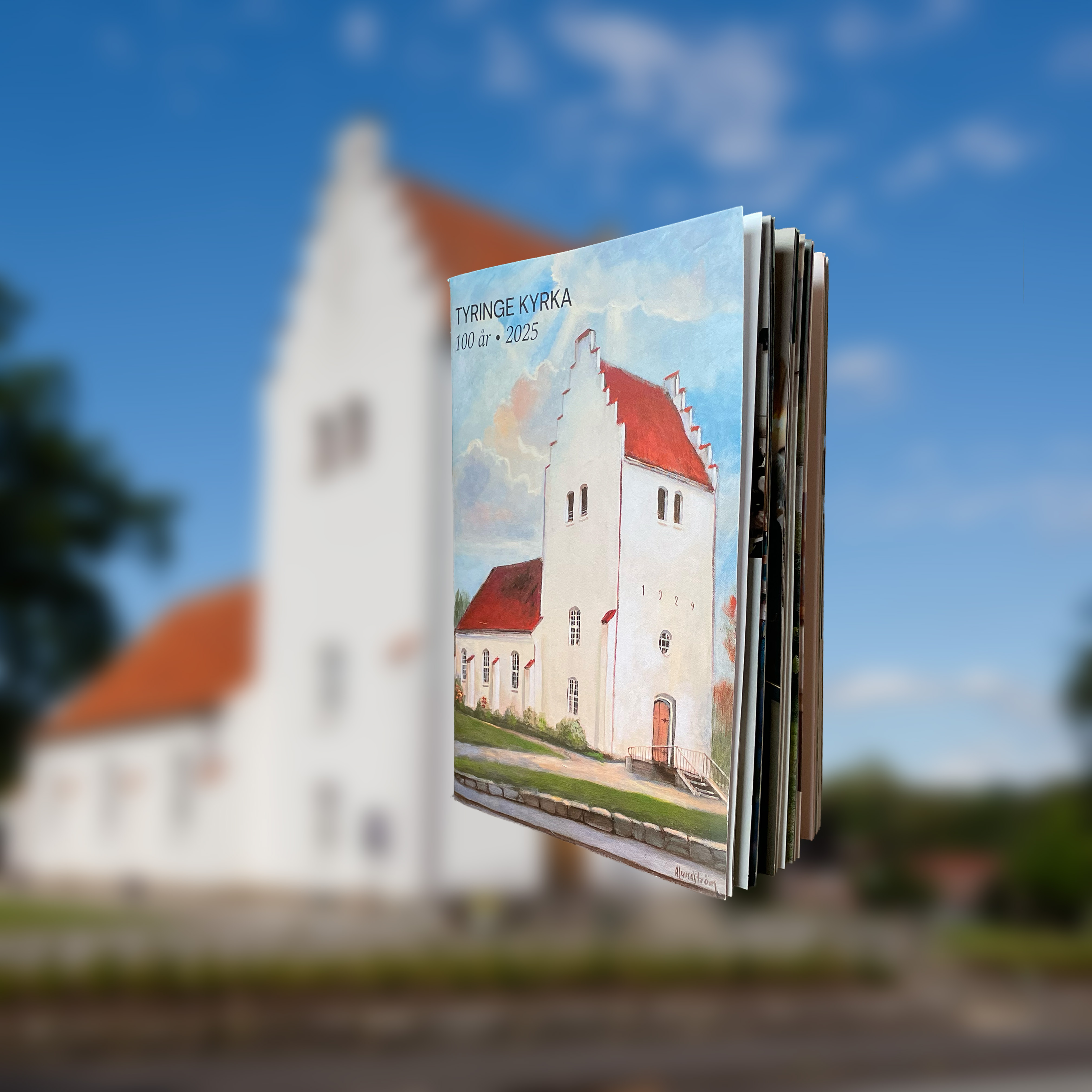 En liten bok med en kyrka på omslaget. I bakgrunden syns samma kyrka som på boken.