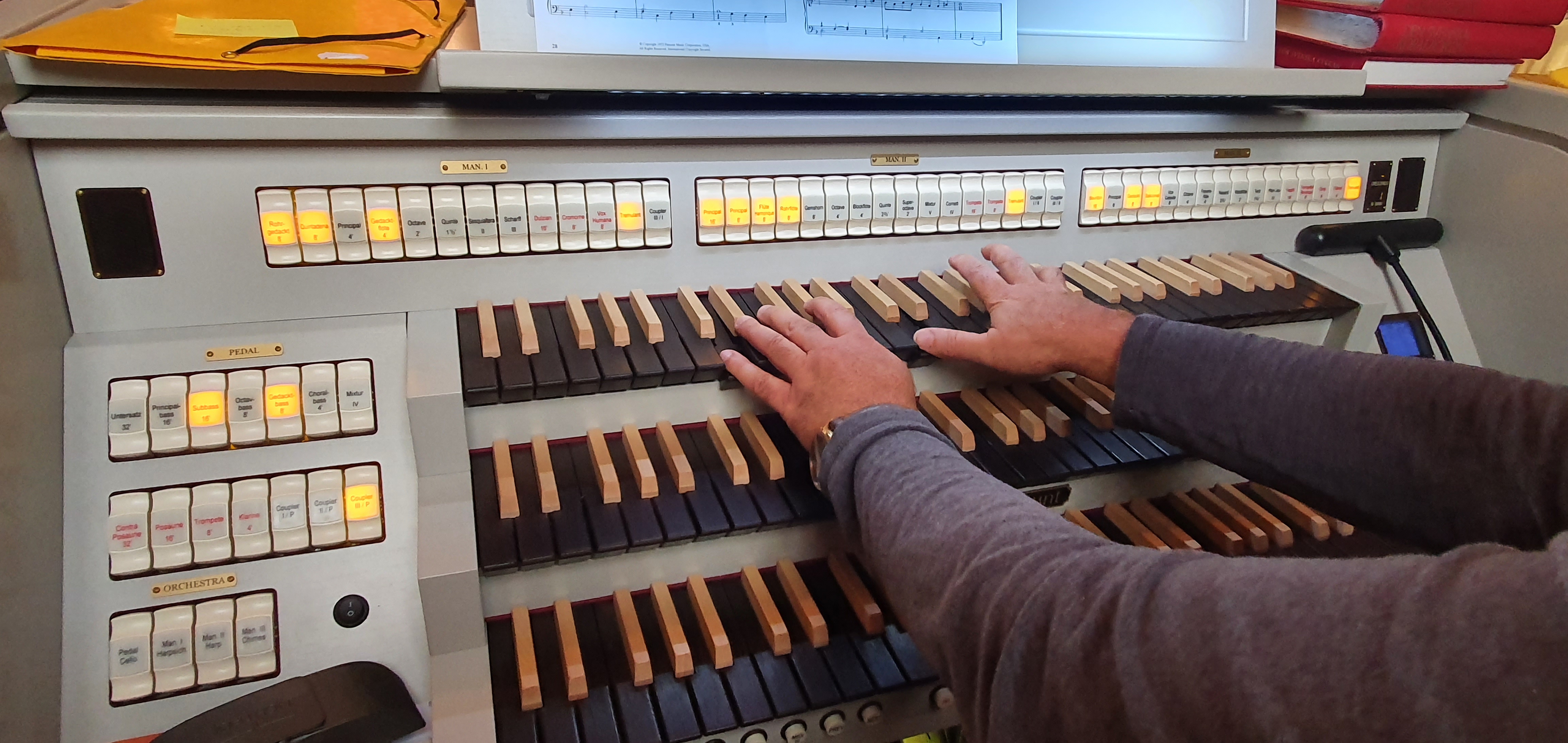 El-orgels klaviatur med kyrkomusikers händer som spelar