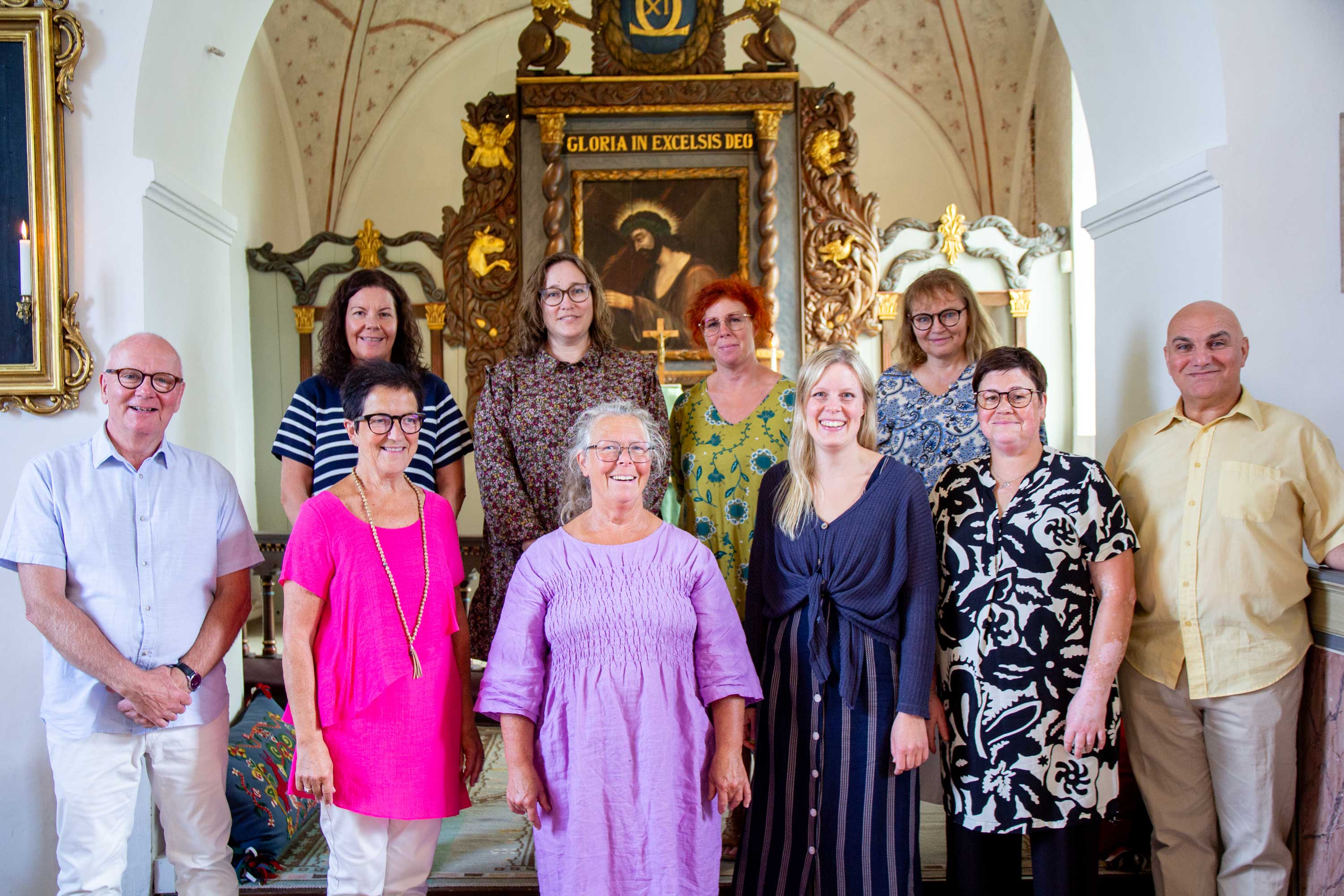 Kören står i kör-uppställning vid koret i Rinkaby kyrka