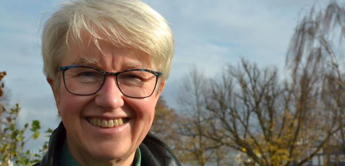 Diakonen Britt Jonasson utomhus med ett höstlandskap i bakgrunden.