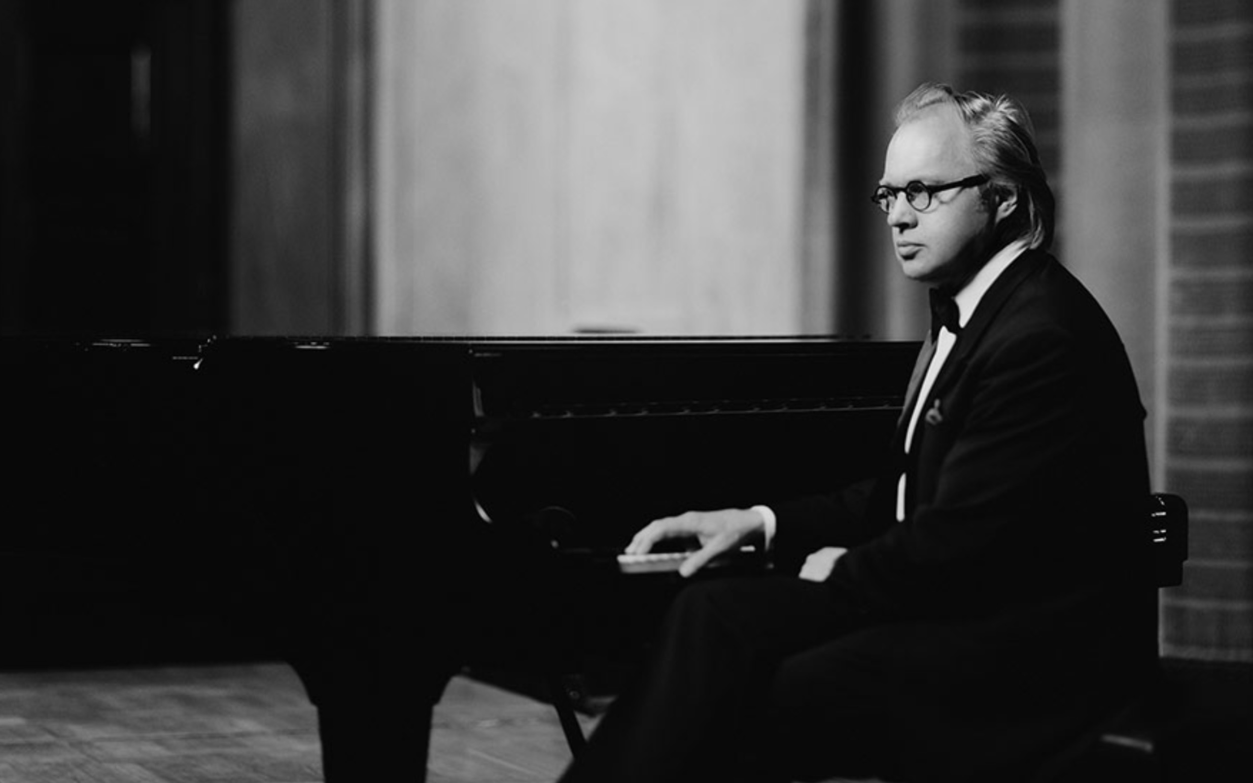 Svartvitt foto där en pianist sitter vid en flygel