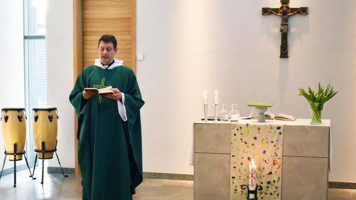 En präst står bredvid ett altare och läser.