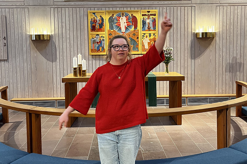 en ung kvinna står vid altarringen och pekar uppåt med fingret