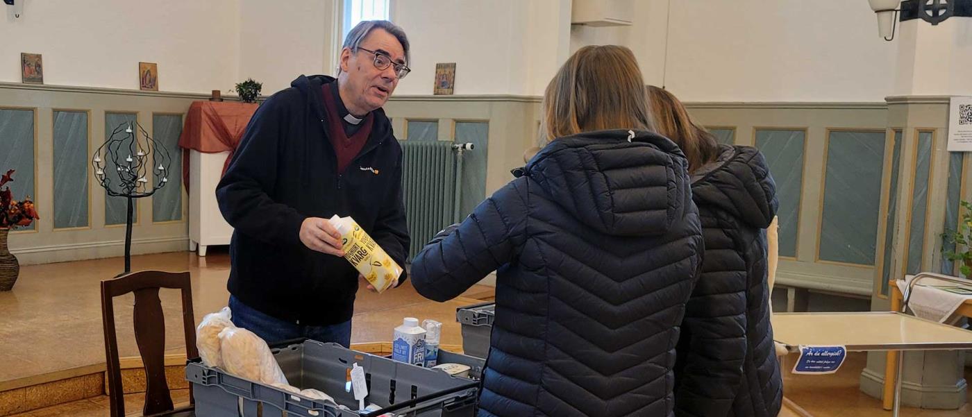 John Sund delar ut mat till besökare på matbanke