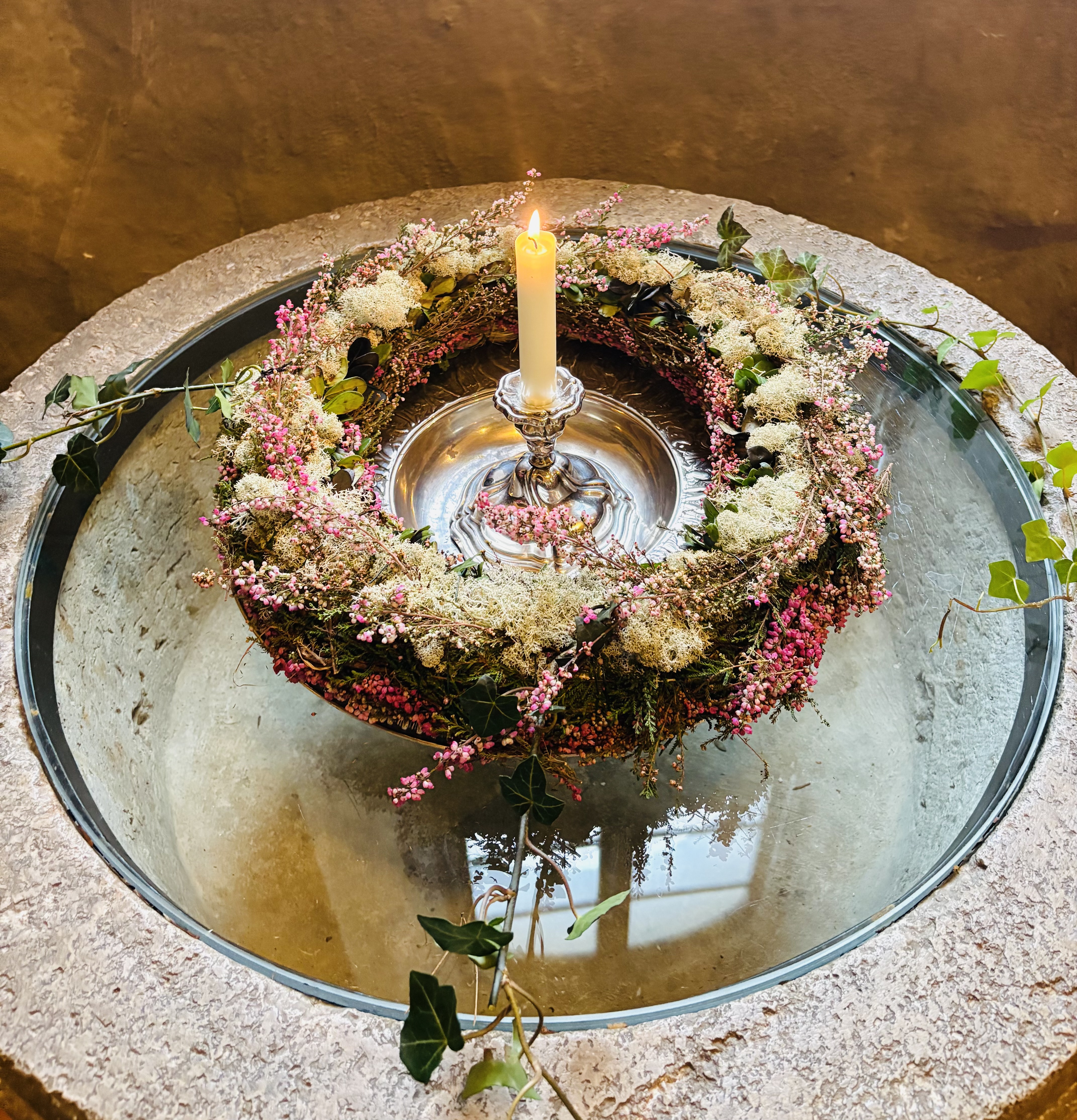 Krans med ljus i en dopfunt i Husby-Ärlinghundra kyrka.
