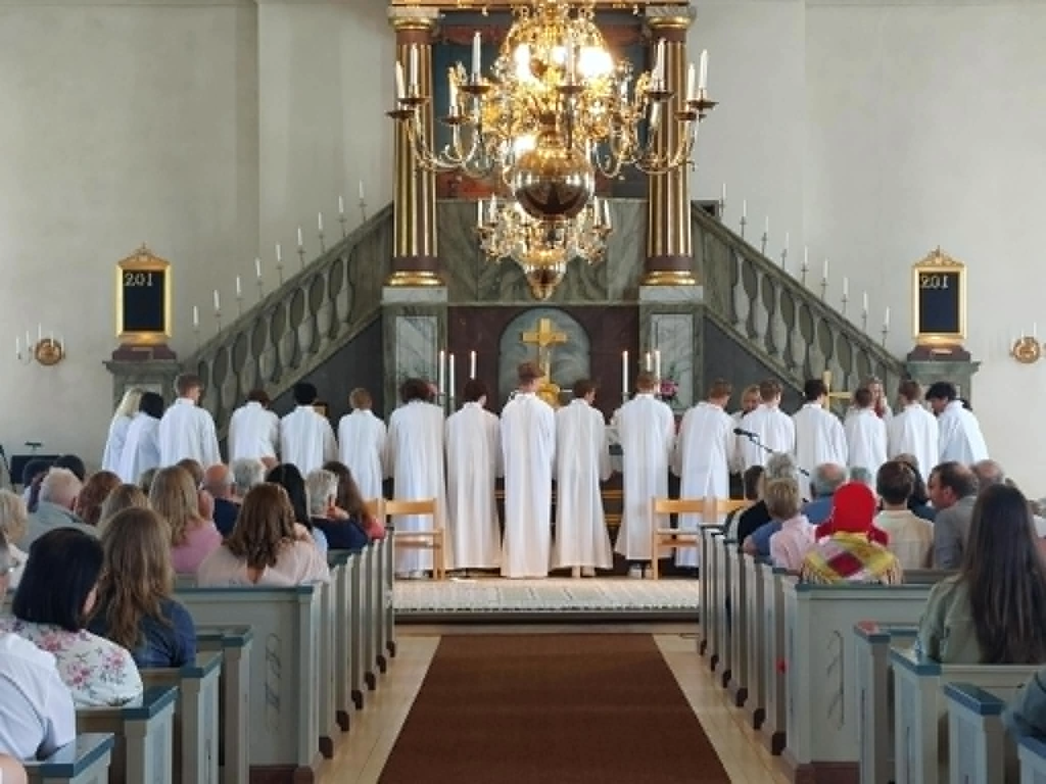 Konfirmander uppställda vid altarringen.