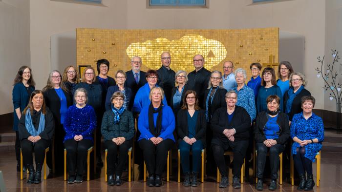 Kyrkokören klädd i blått och svart framför altaret i Trönö kyrka