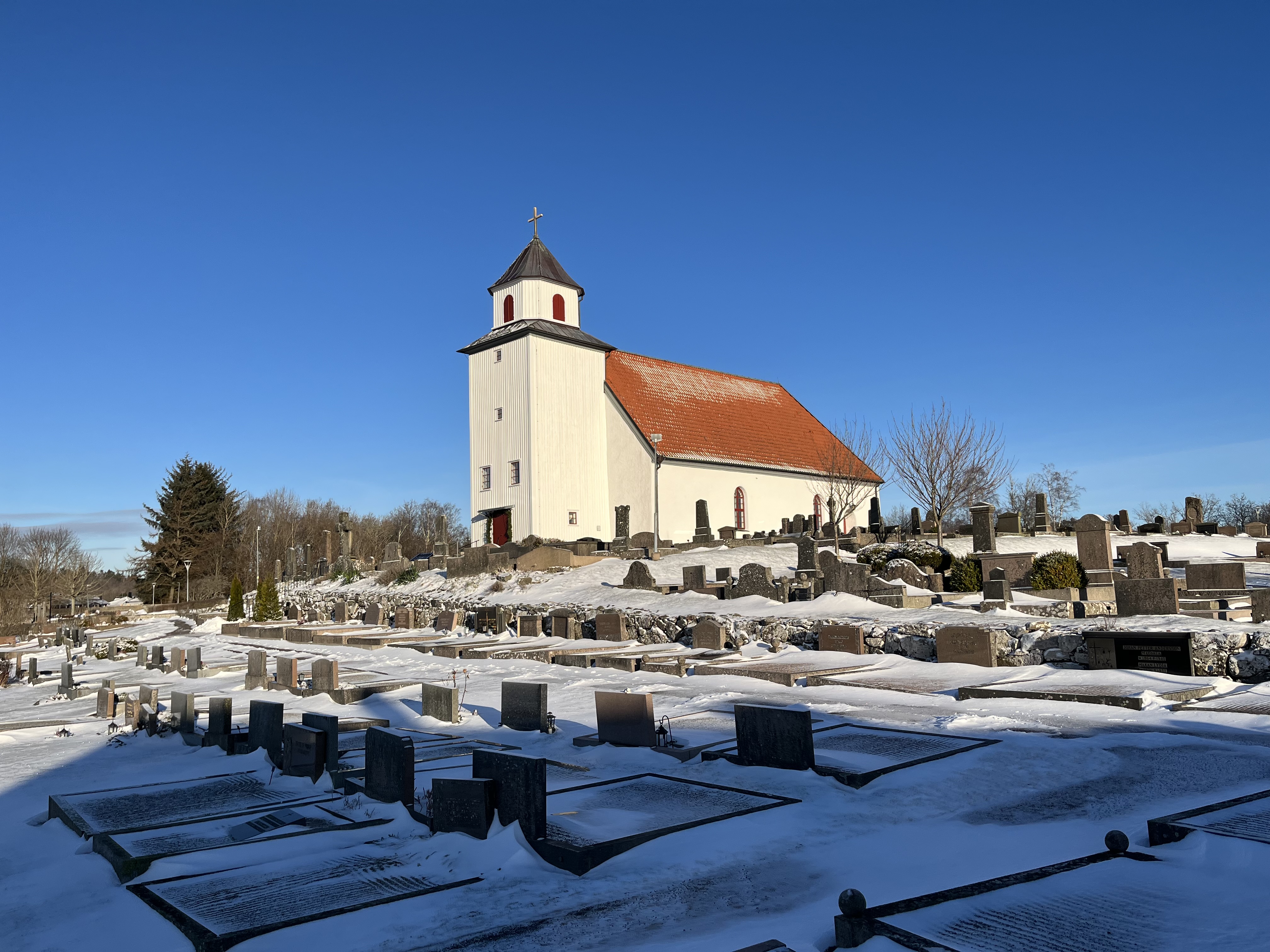 Romelanda kyrka med ett tunt snötäcke och blå himmel
