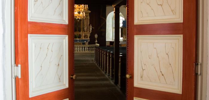 Portarna från vapenhuset in i kyrkan i Stora Lundby kyrka står på glänt.
