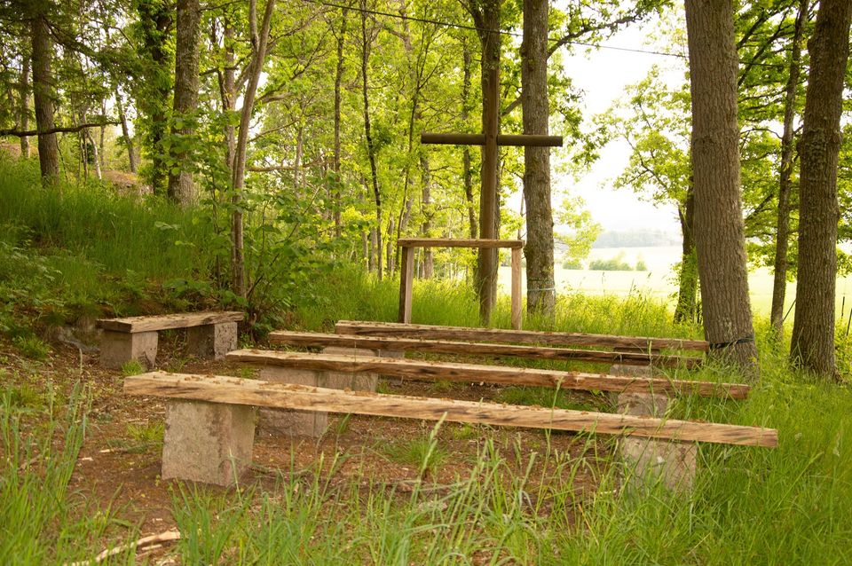 Friluftskyrka med bänkar och altare ute i en skogsdunge vid Östad församlingshem.