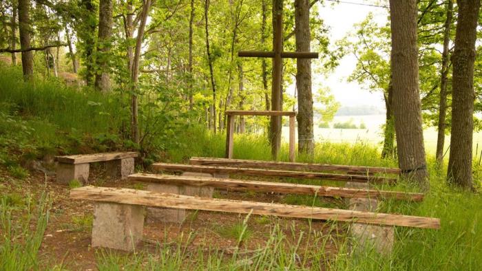 Friluftskyrka med bänkar och altare ute i en skogsdunge vid Östad församlingshem.