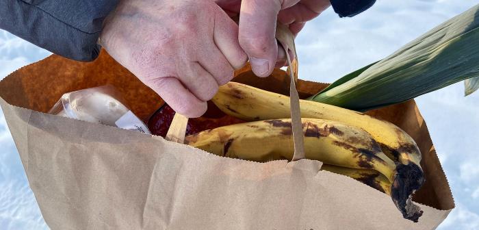 Överlämnade av en matkasse med bananer och purjolök som sticker upp.