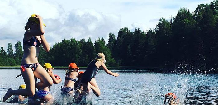 Barn som hoppar från bryggan ner i vattnet så det stänker