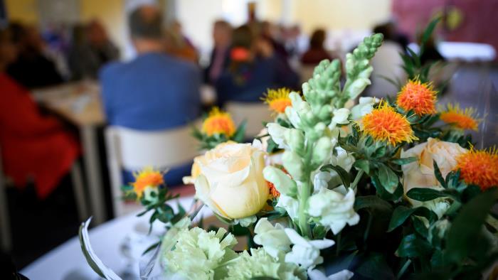 Människor i samtal, blommor på bord