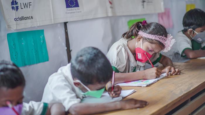 Skrivande barn i skolbänk i Myanmar