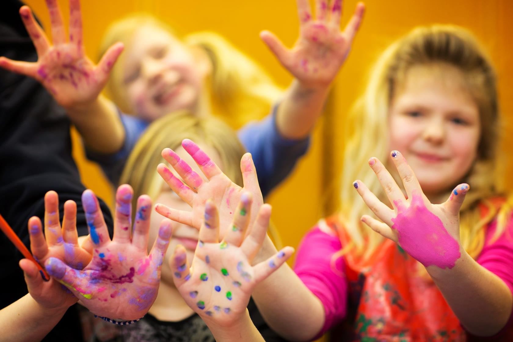 Barn med färgglada händer