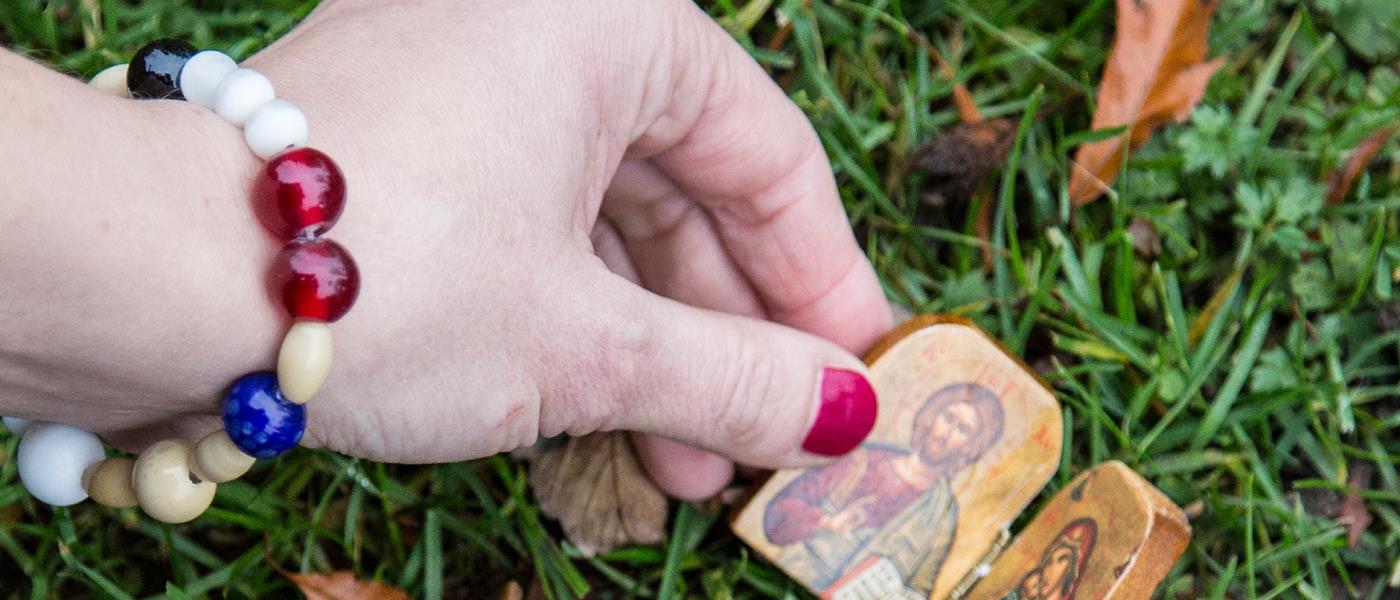 Hand med frälsarkransarmband som håller liten Jesusikon