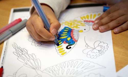 Barns hand som målar en teckning med tuschpenna.