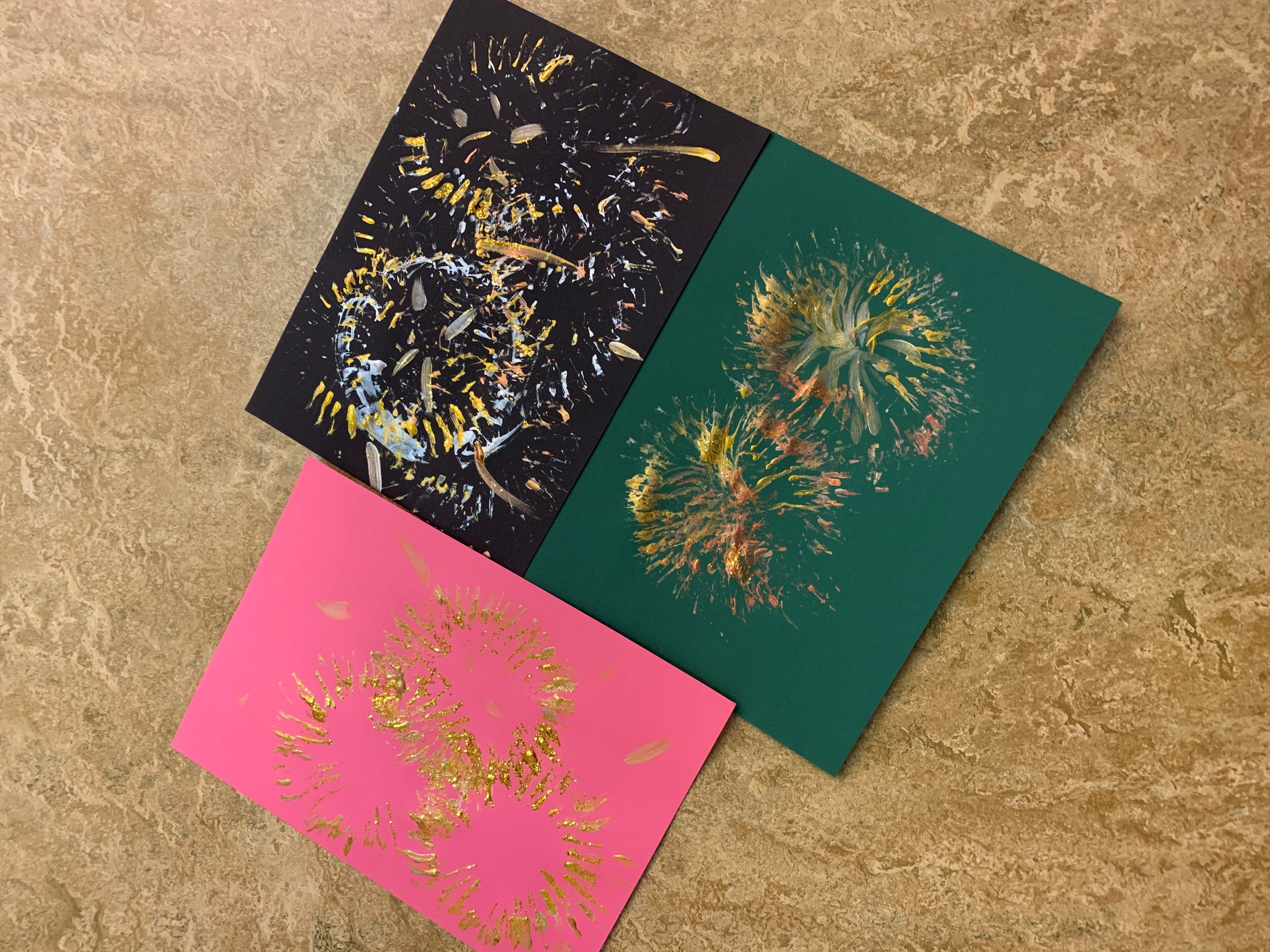 Kort i svart, grönt och rosa med målat fyrverkeri.