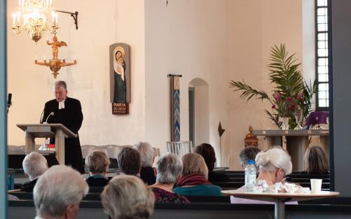 Biskop Åke Bonnier vid ambon, talarstolen, i Tidaholms kyrka och talar till församlingen, klädd i en svart kaftan.