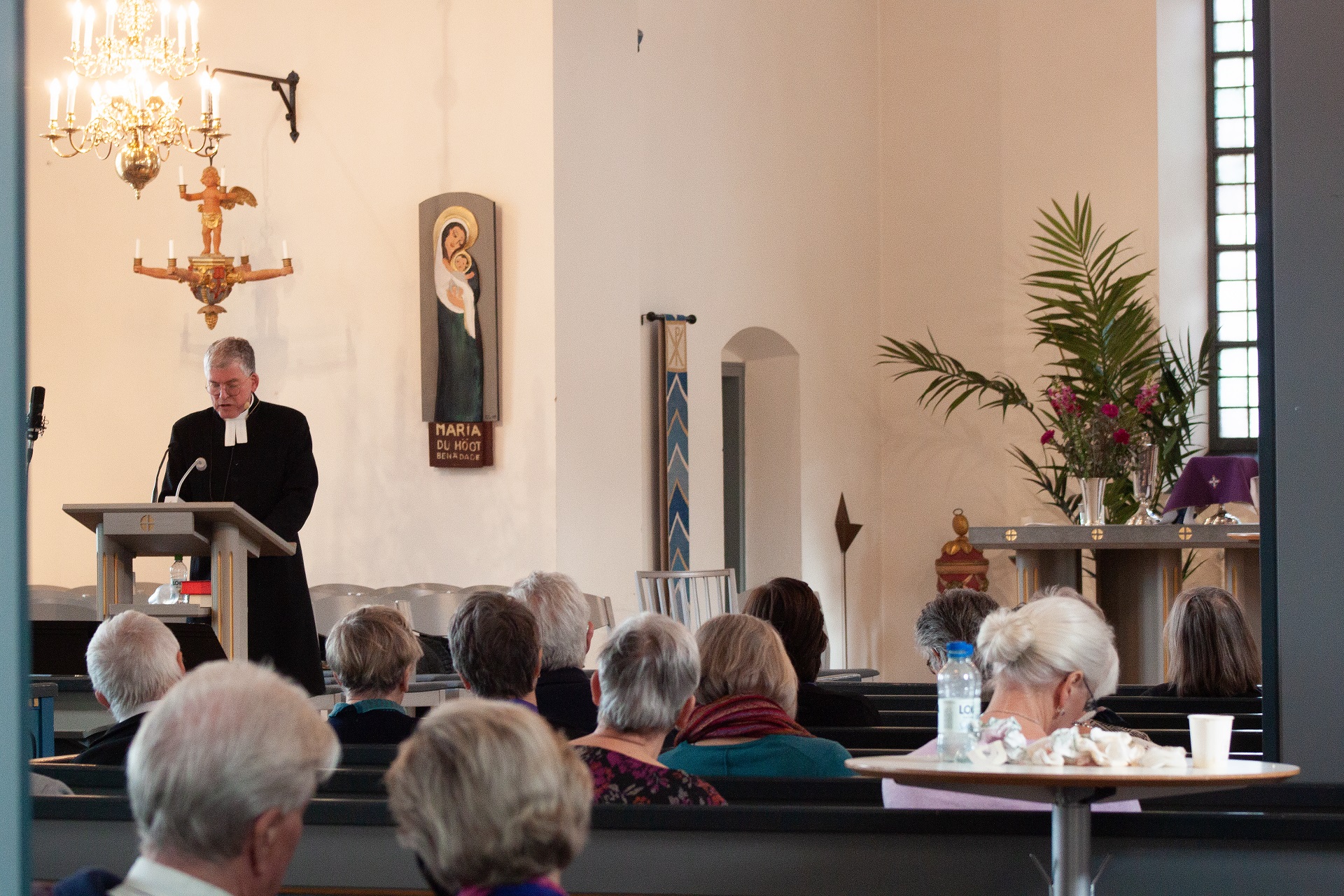 Biskop Åke Bonnier vid ambon, talarstolen, i Tidaholms kyrka och talar till församlingen, klädd i en svart kaftan.
