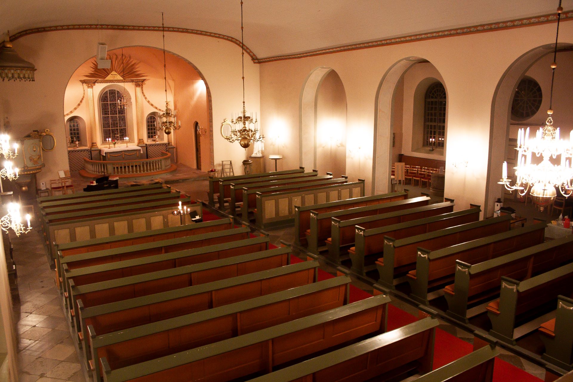Kyrkbänkar och altare i en kyrka, bild tagen uppifrån läktaren.