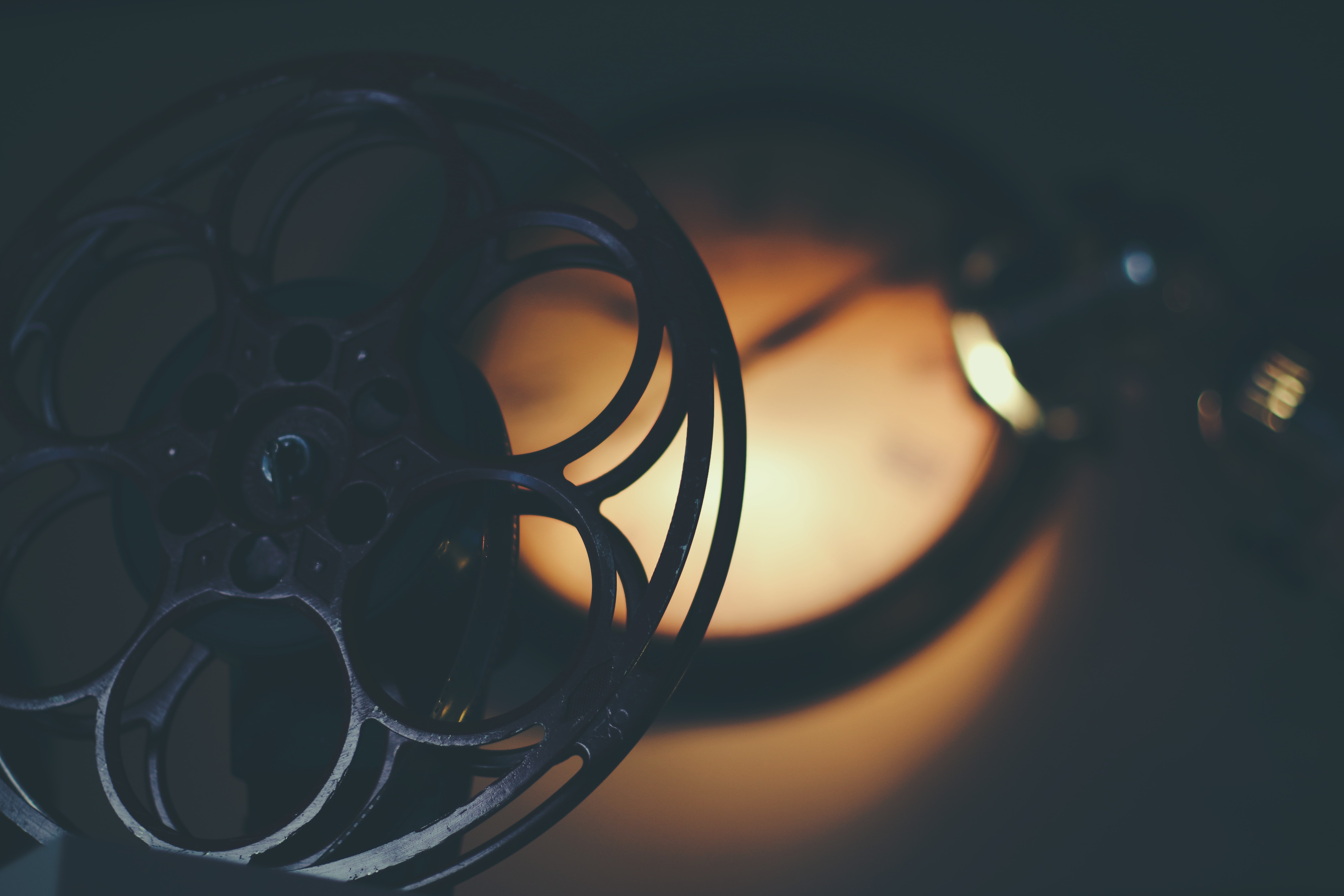 En siluett av en gammeldags filmrulle, i bakgrunden lyser ett ljussken.