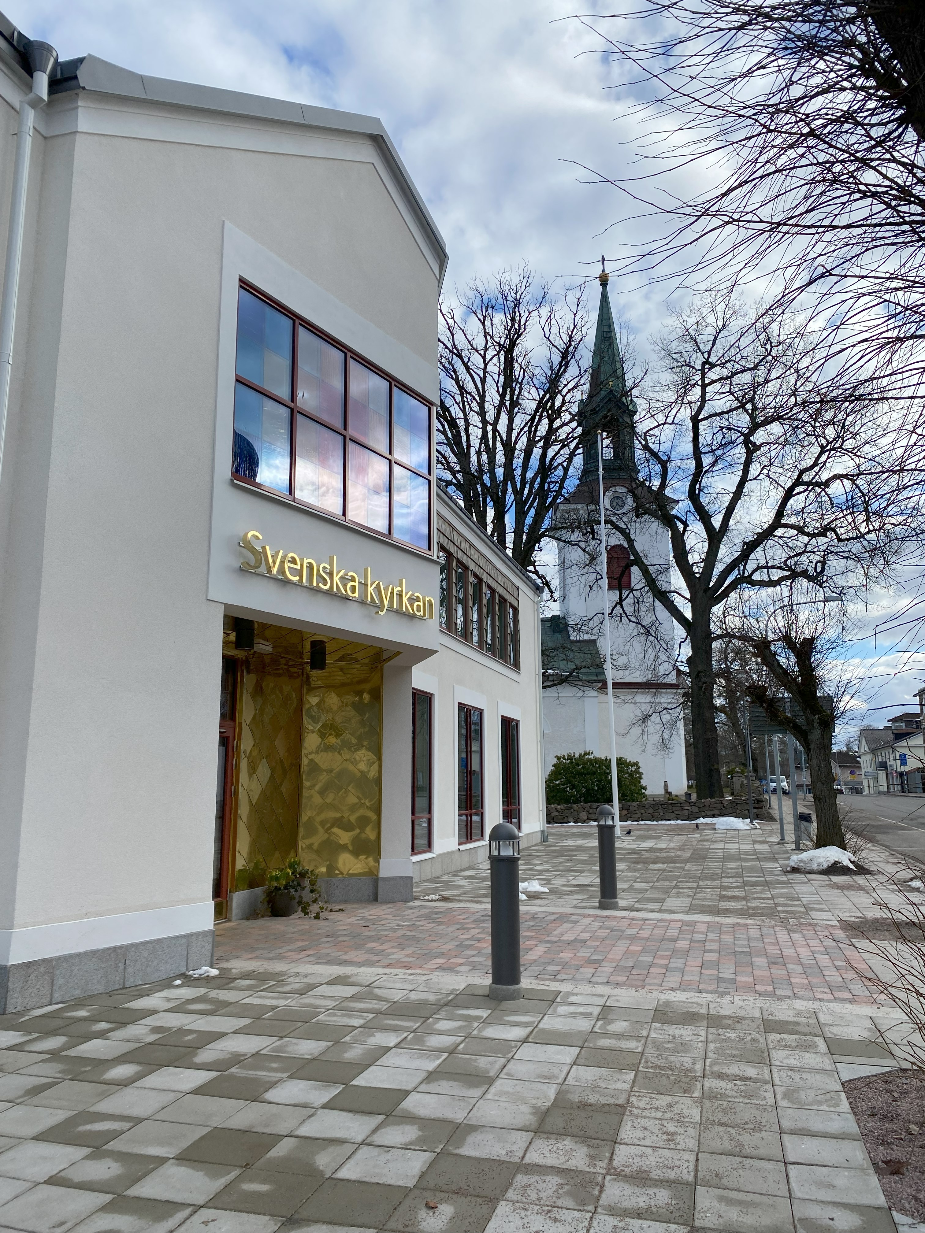 En gågata som går förbi Kyrkans hus i Tidaholm, på huset syns skylten "Svenska kyrkan" och entrén.