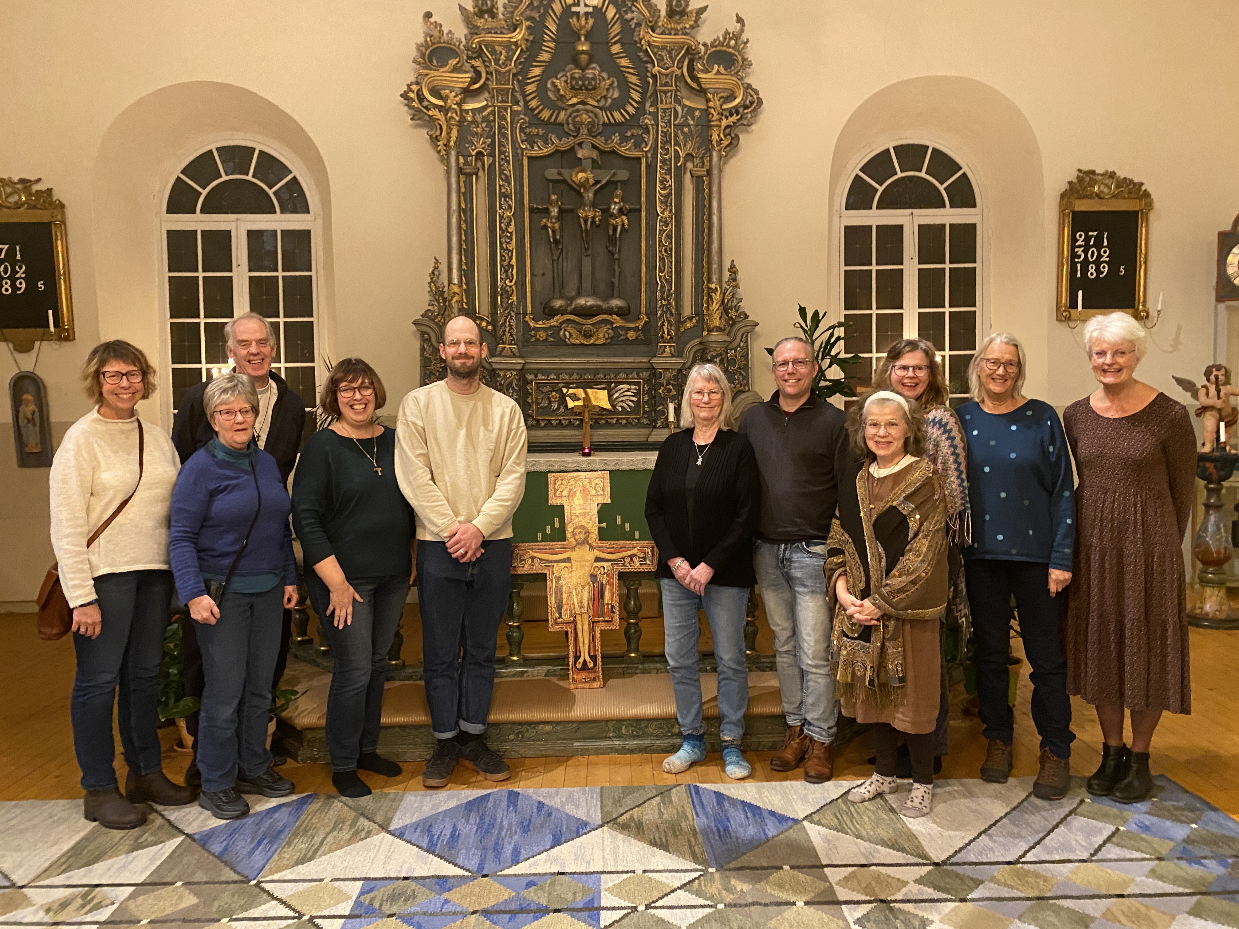 Gruppbild med elva vucna människor som står i koret i en kyrka.