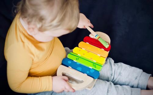 Ett barn sett snett uppifrån som spelar på en flerfärgad xylofon.