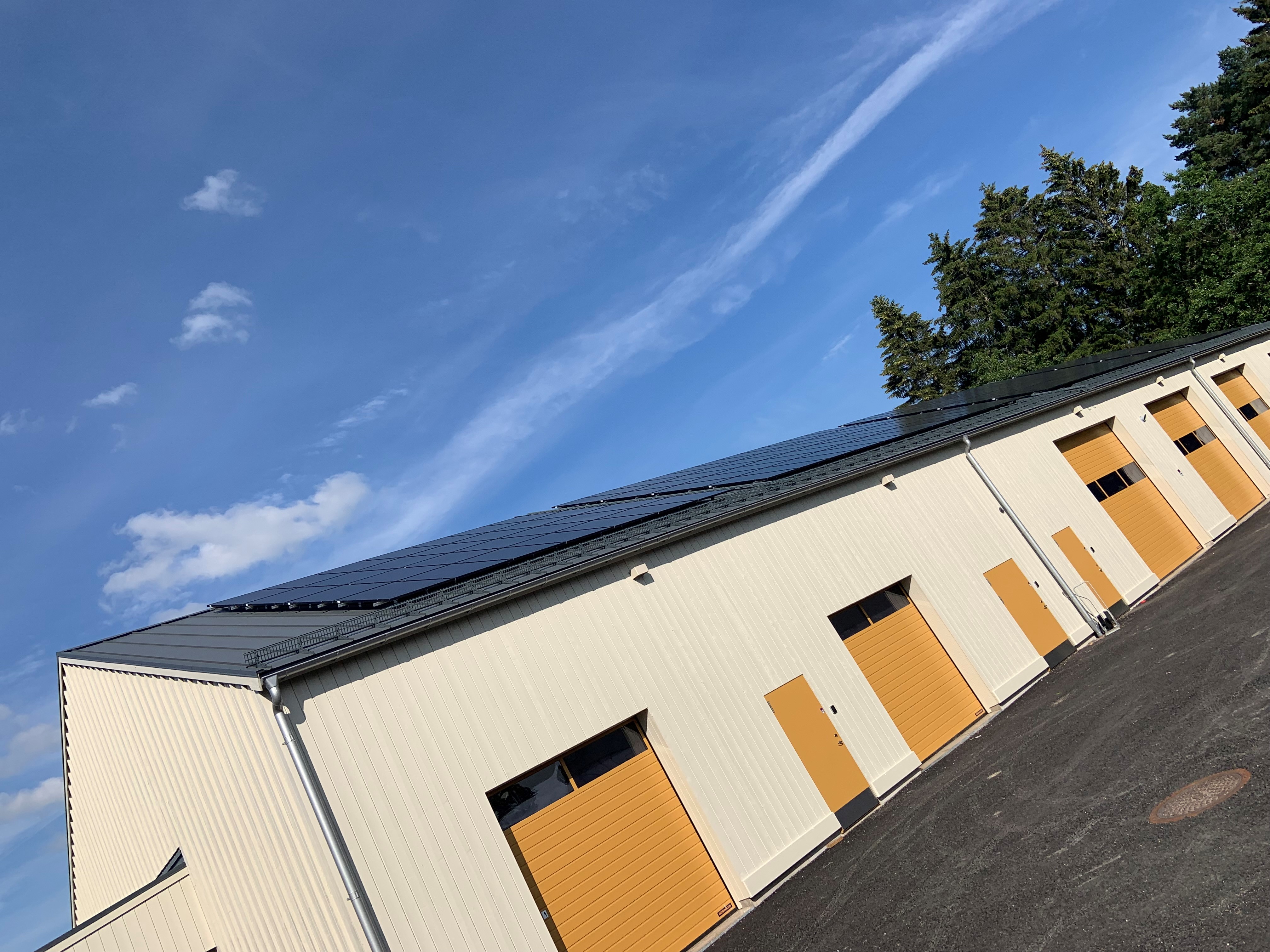 En vit byggnad med gula garageportar och solpaneler på taket.